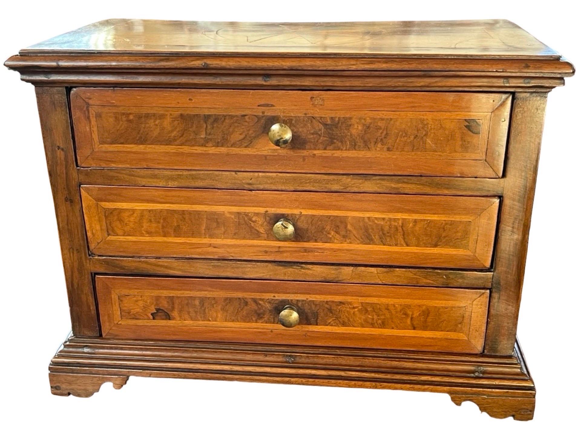 Miniature chest of drawers handcrafted in Italy in the early 1800s using walnut. Despite being small, the chest shows all the elements of a large commode, and it may have been crafted originally as a showcase for a carpenter or custom cabinet maker.