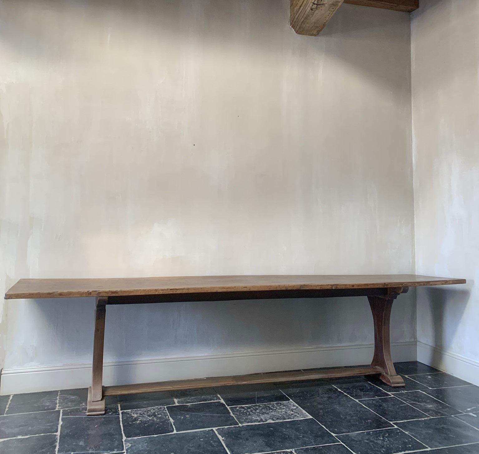 A large 19th century Italian walnut refectory console table. The top of one solid piece of beautifully grained walnut. Subtle patina and verry sturdy. The top on one corner slightly warped. 
Elegant base handpegged with the same wood for the