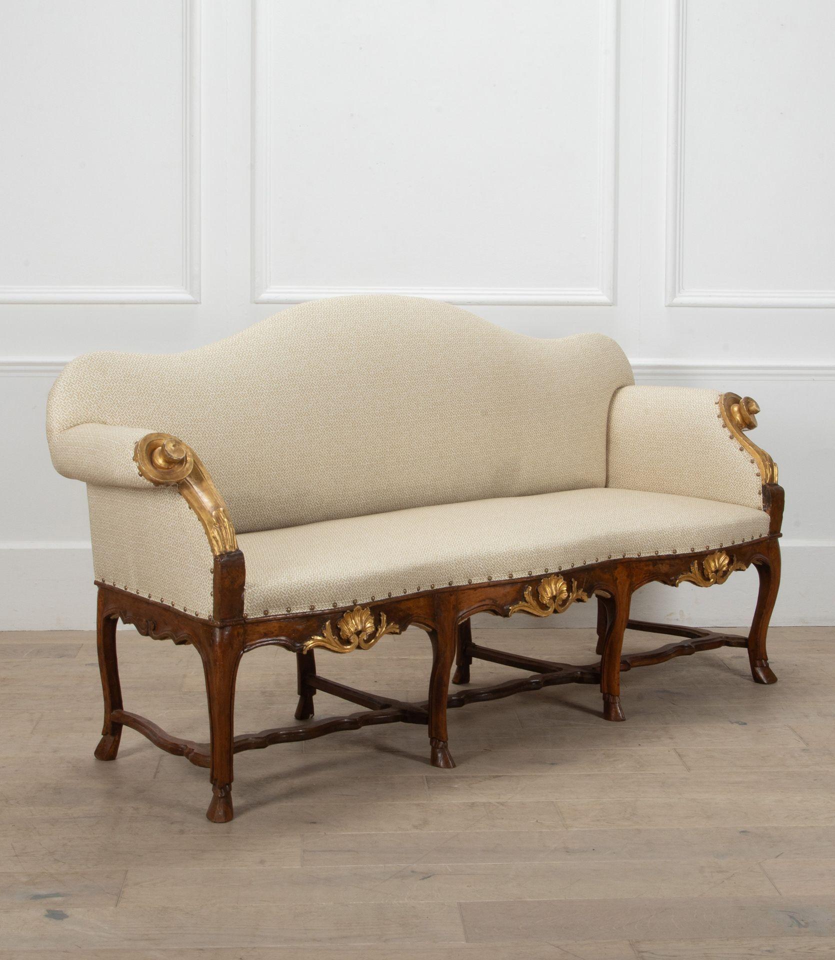 Elegant early 19th Century Italian, Northern Tuscan, sofa.
With gently curved back and gilded scroll details to each arm.
Of walnut construction with hand carved details to each leg, terminating in hoof feet with more gilded decoration to the