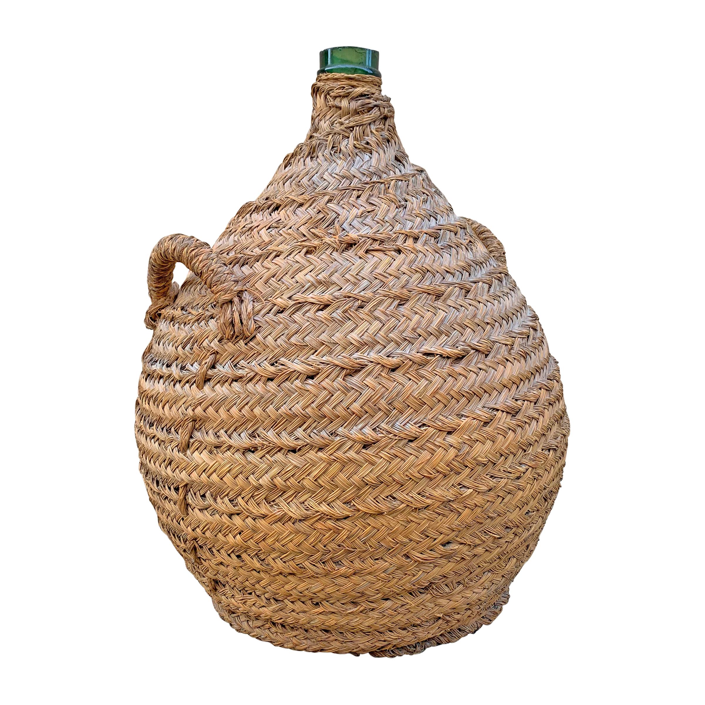 A handsome 19th century Italian hand blown green glass wine jar covered in a handwoven wicker basket to protect from bumps and bruises.