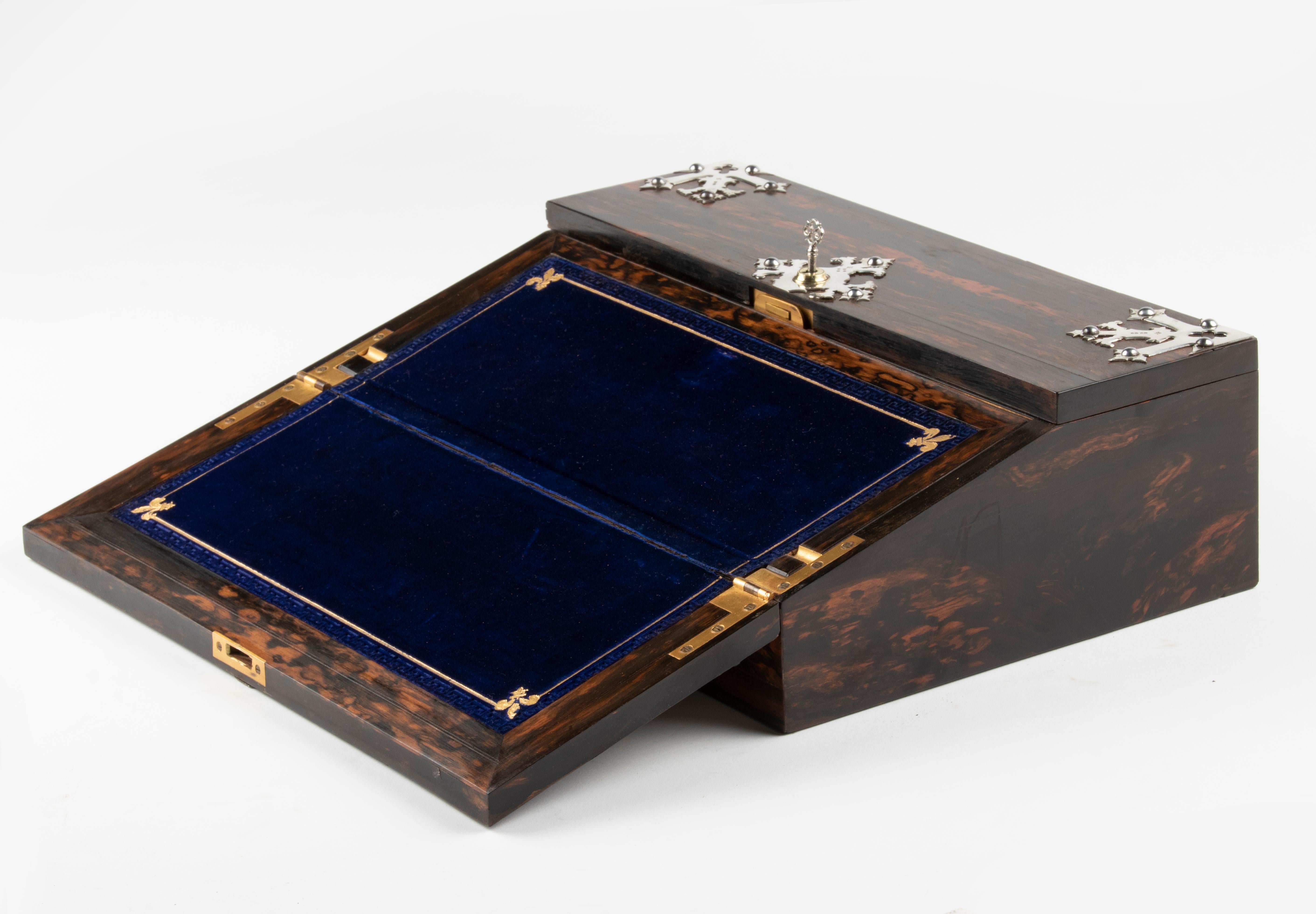 Precioso estuche antiguo para pendientes de escribir. El arcón está chapado en madera de Macassar. Decorado con monturas de plata. El interior es de madera de arce alpina. La vertiente tiene un forro de terciopelo azul oscuro. Con cerradura y llave