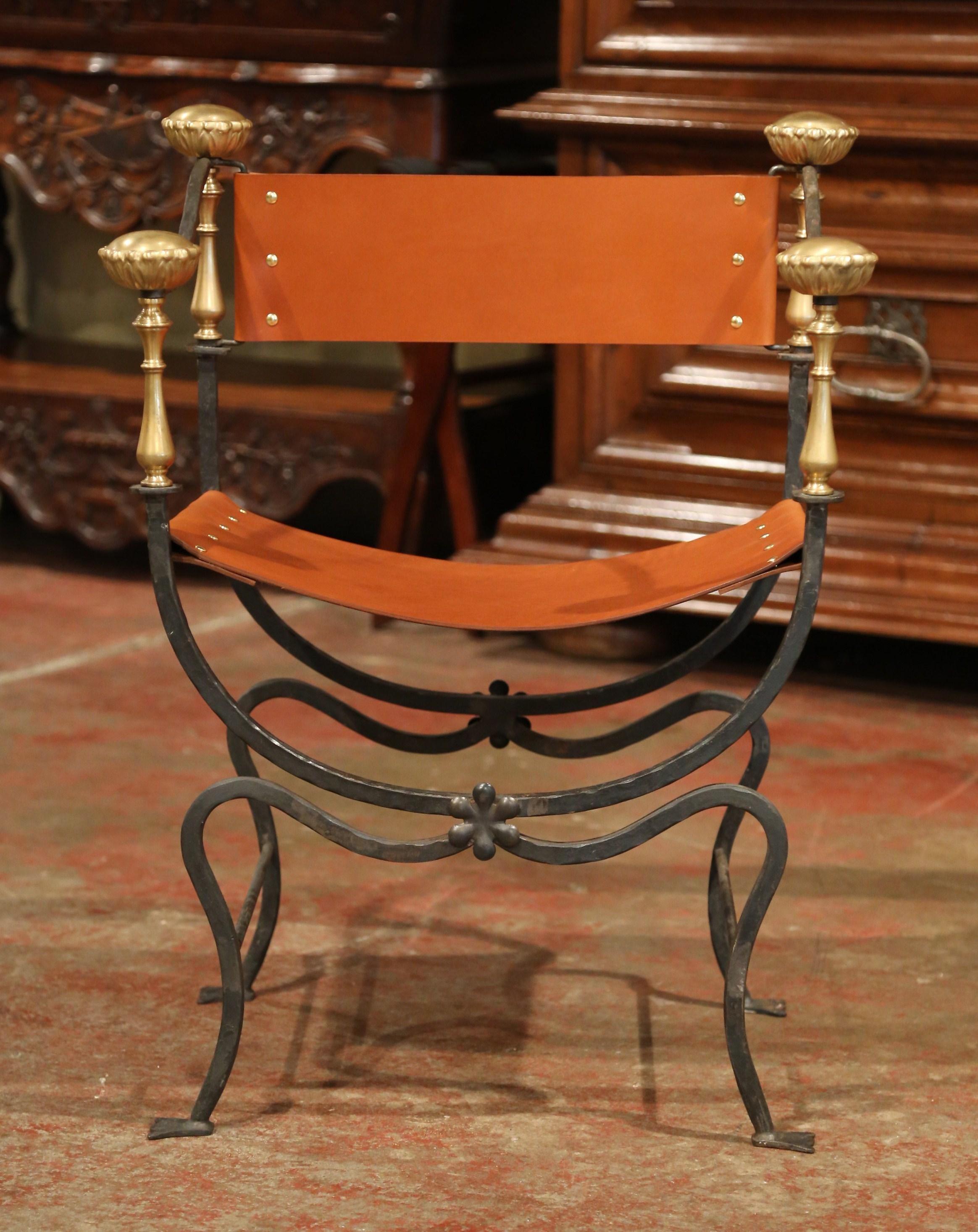 This elegant, antique Campaign armchair was created in Italy, circa 1880. The frame of the chair is formed from forged iron; the piece has scrolled legs, and is embellished with decorative bronze rosette finials on each armrest and the back. Both