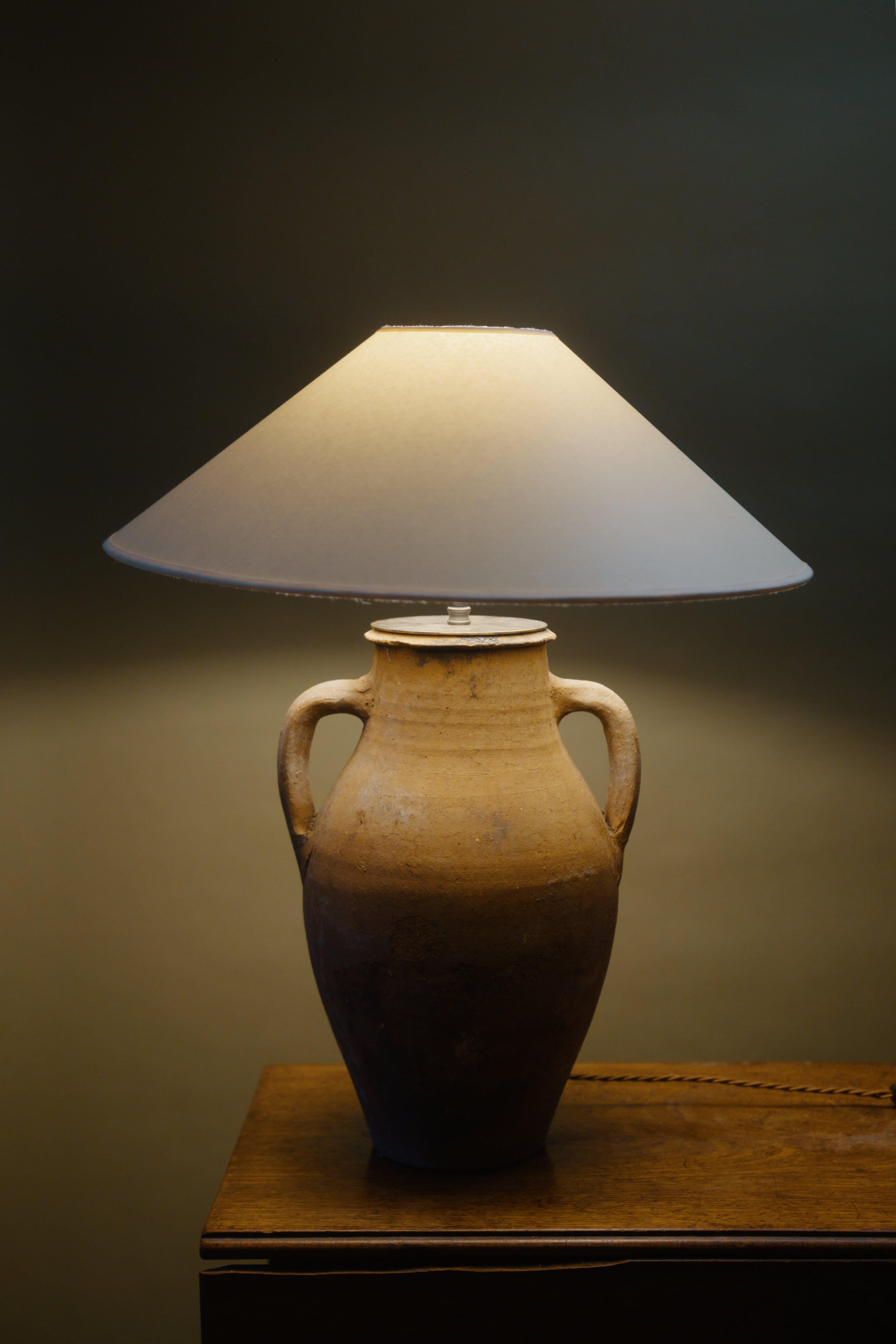 This 19th century Izmir utility pot lamp combines artisan craftsmanship with a simple yet timeless design. Handcrafted from a vintage Mediterranean clay pot, it features a natural, weathered finish that adds character and charm, perfect for country