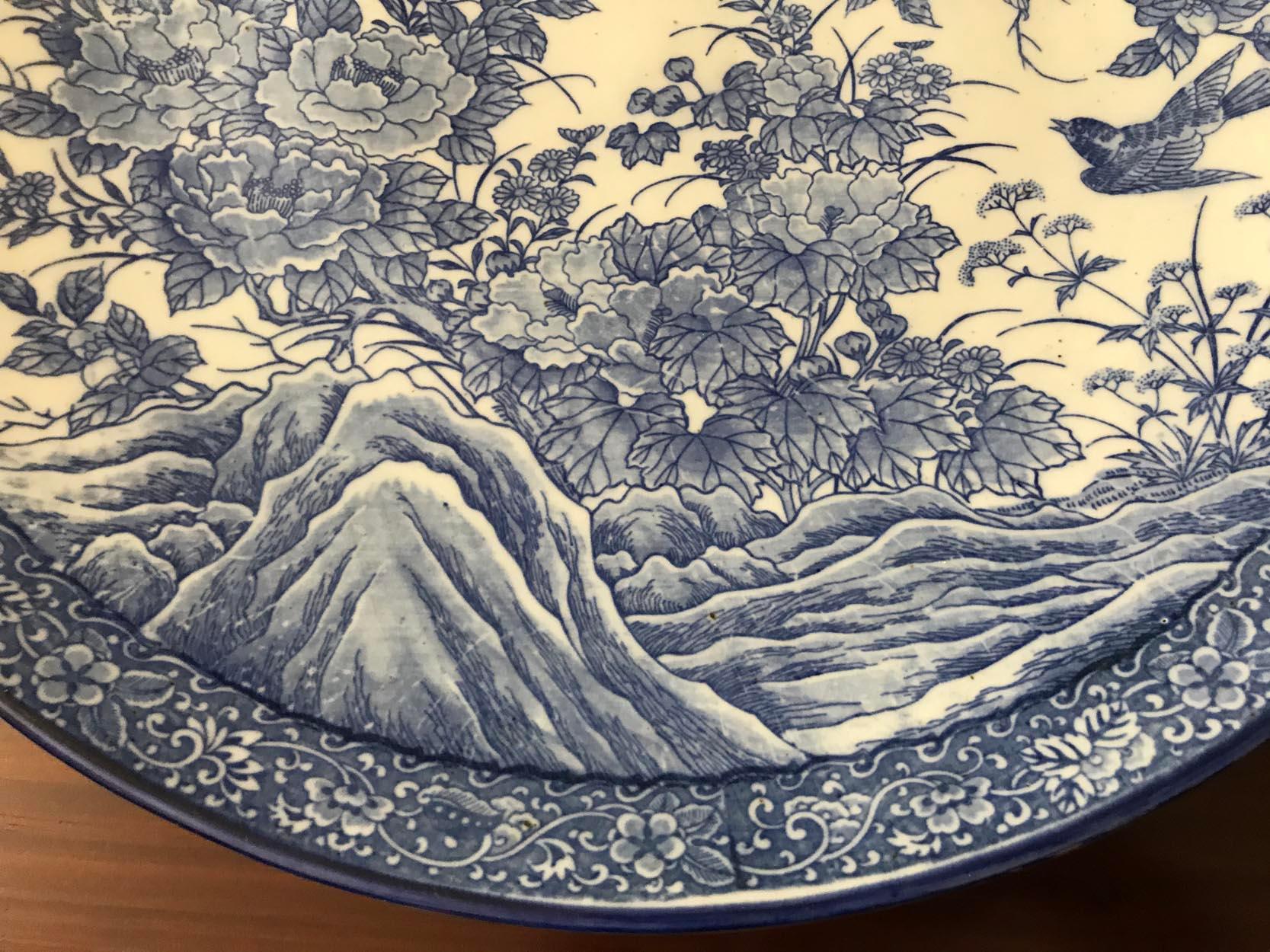 Meiji-period porcelain charger is ornamented in cobalt blue with a floral design incorporating a rocky outcrop, tree, chrysanthemums and a swooping swallow, with a decorative floral border.

In good condition with no chips, cracks and minimal wear.