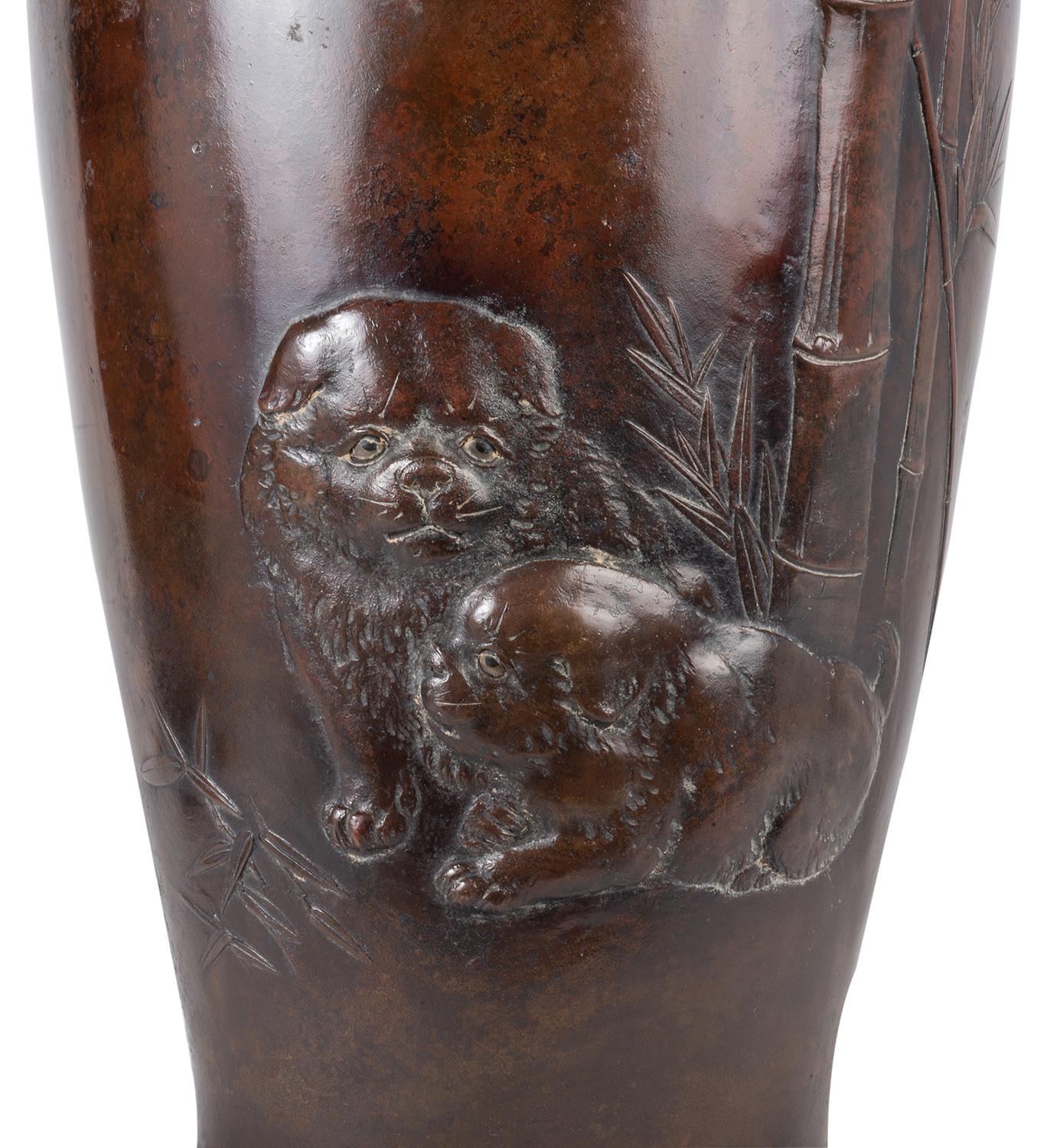 A very good quality Meiji period (1868-1912) Japanese patinated bronze vase, depicting two seated dogs below a Bamboo plant.