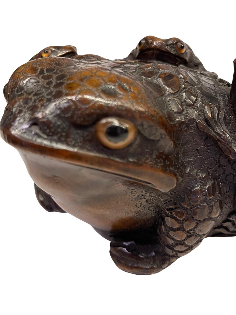 19th century Japanese carved wood sculpture of Toads from the Edo Period. Finely carved as three small toads on top of a large toad, the surface finished to resemble the toad's rugged skin, signature on underside. The piece is signed on the bottom