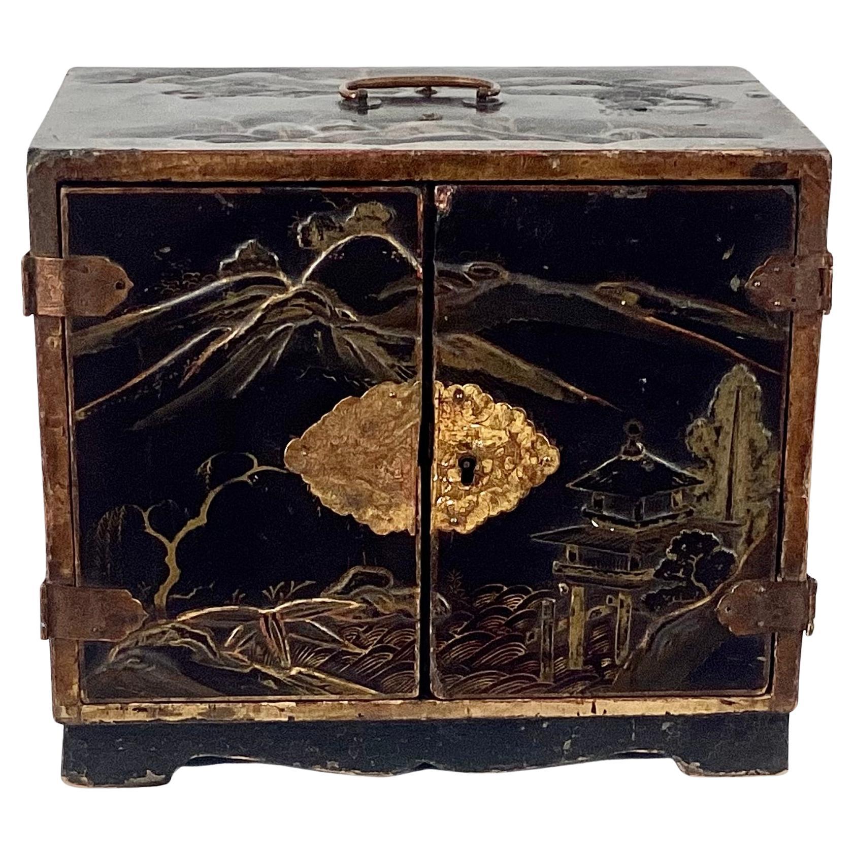 19th century Japanese chinoiserie painted gold lacquer. chest with brass handle. Chest depicts Japanese countryside and mountains in raised chinoiserie design. Twin front doors open to four decorated drawers, perfect for holding jewelry and other