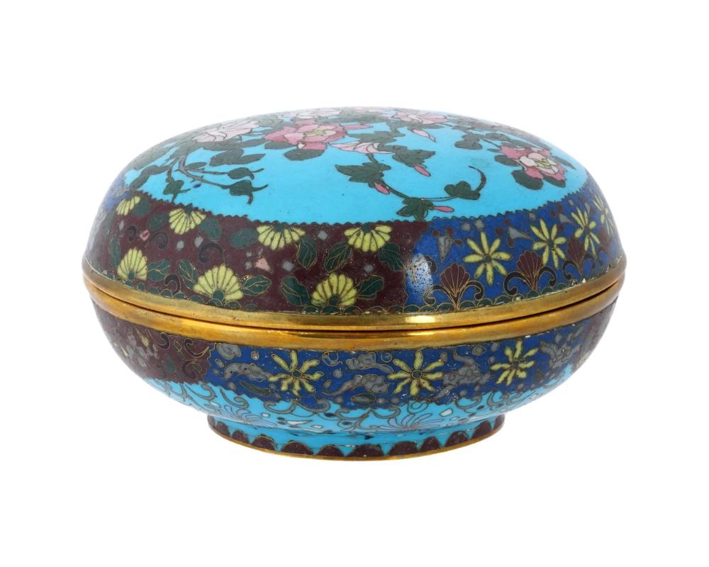 An antique Japanese, late Meiji era, covered enamel over brass jewelry or trinket box. The exterior of the ware is enameled with polychrome images of blossoming flowers surrounded by a foliate scroll ornament made in the Cloisonne technique. The