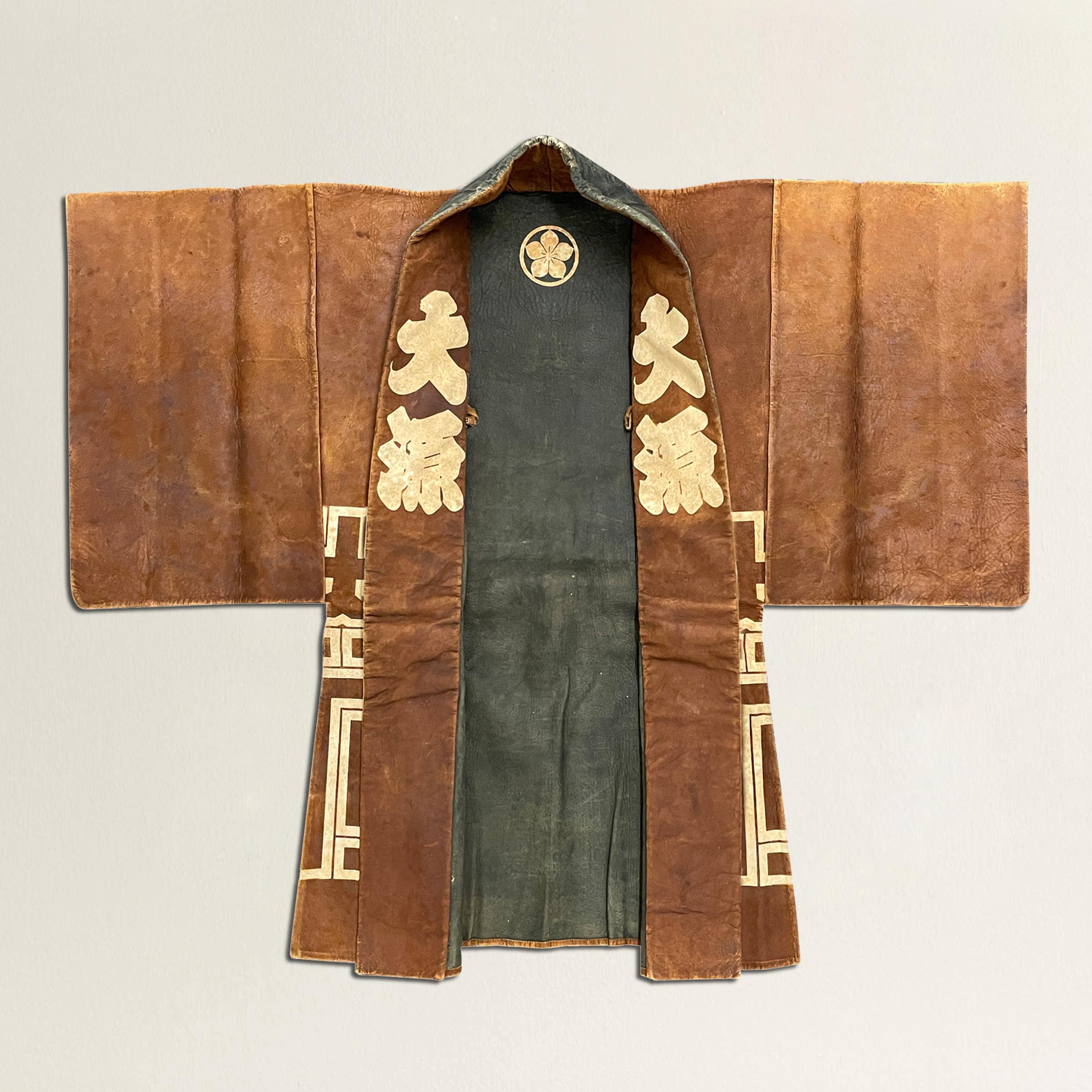 A rare 19th century Japanese firemen's coat, constructed from smoked deer leather and with bold white stenciled characters creating a wonderfully modern pattern across the back and bottom portion of the coat. The interior is black and white with