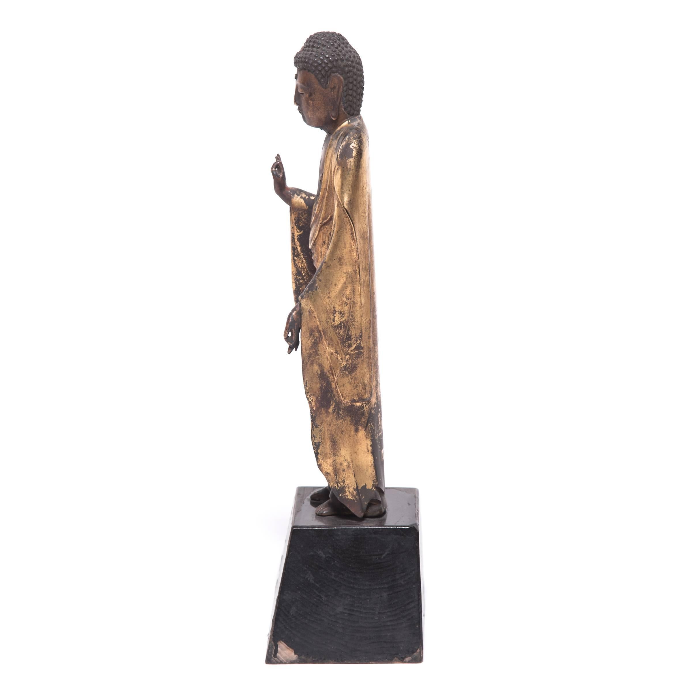 Decorated with black lacquer and gold leaf, this elegant Buddha sculpture was carved from wood in 1875 during Japan’s Meiji Restoration period. The figure presents the classic conventions of representing Buddha - the distended earlobes of his