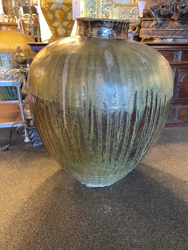 Large scale Japanese ceramic storage jar with beautiful green drip glaze. It takes real skill to fire a jar of this size. The variegated glaze, predominantly shades of dark and lighter green, is dripped over a deep chocolate brown base. 
This jar