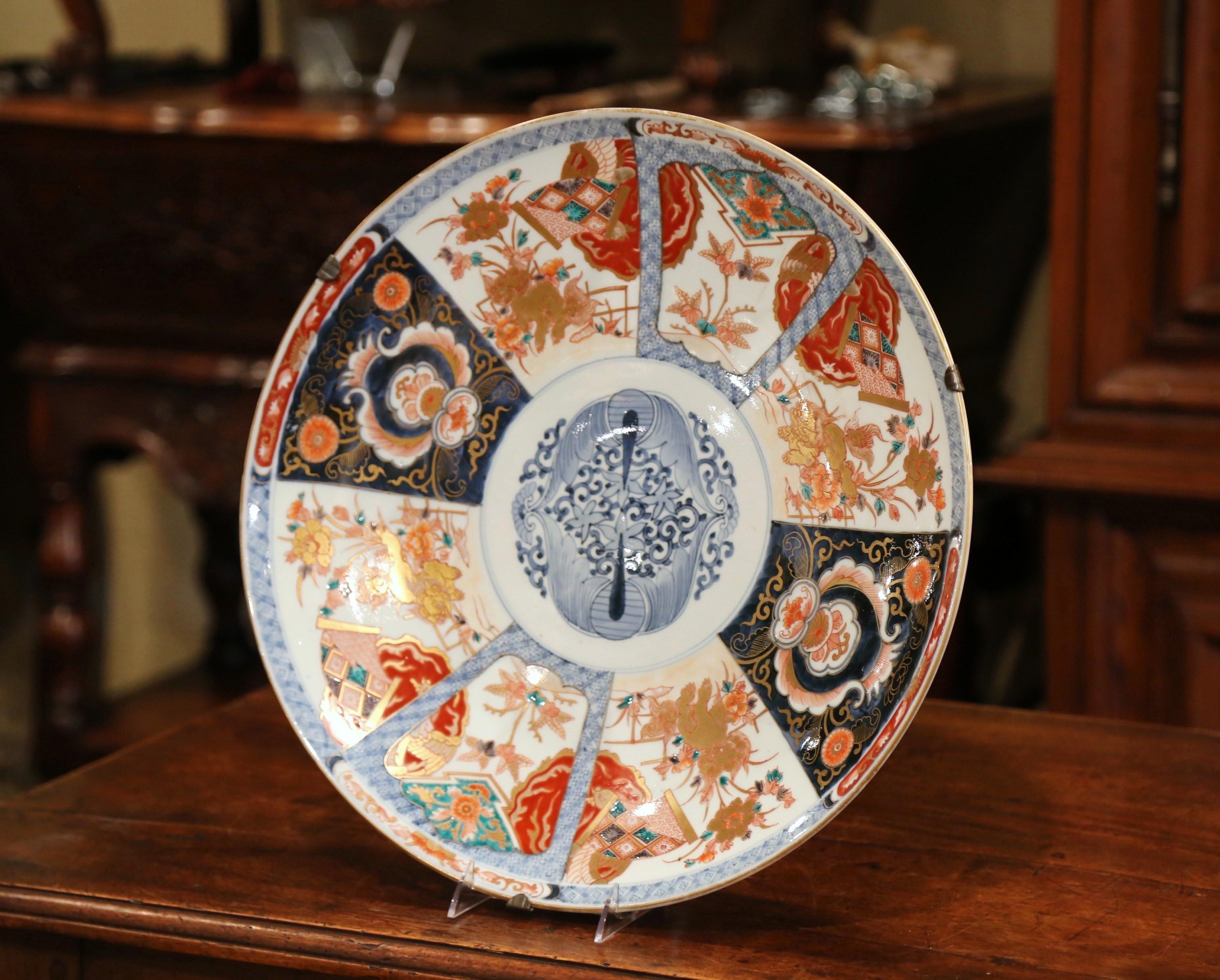 Decorate a wall with this large, porcelain Imari import charger. Crafted in Japan circa 1890, the important Asian ceramic platter features hand painted floral decor with gilt accents. The exotic charger is in excellent condition and has rich,