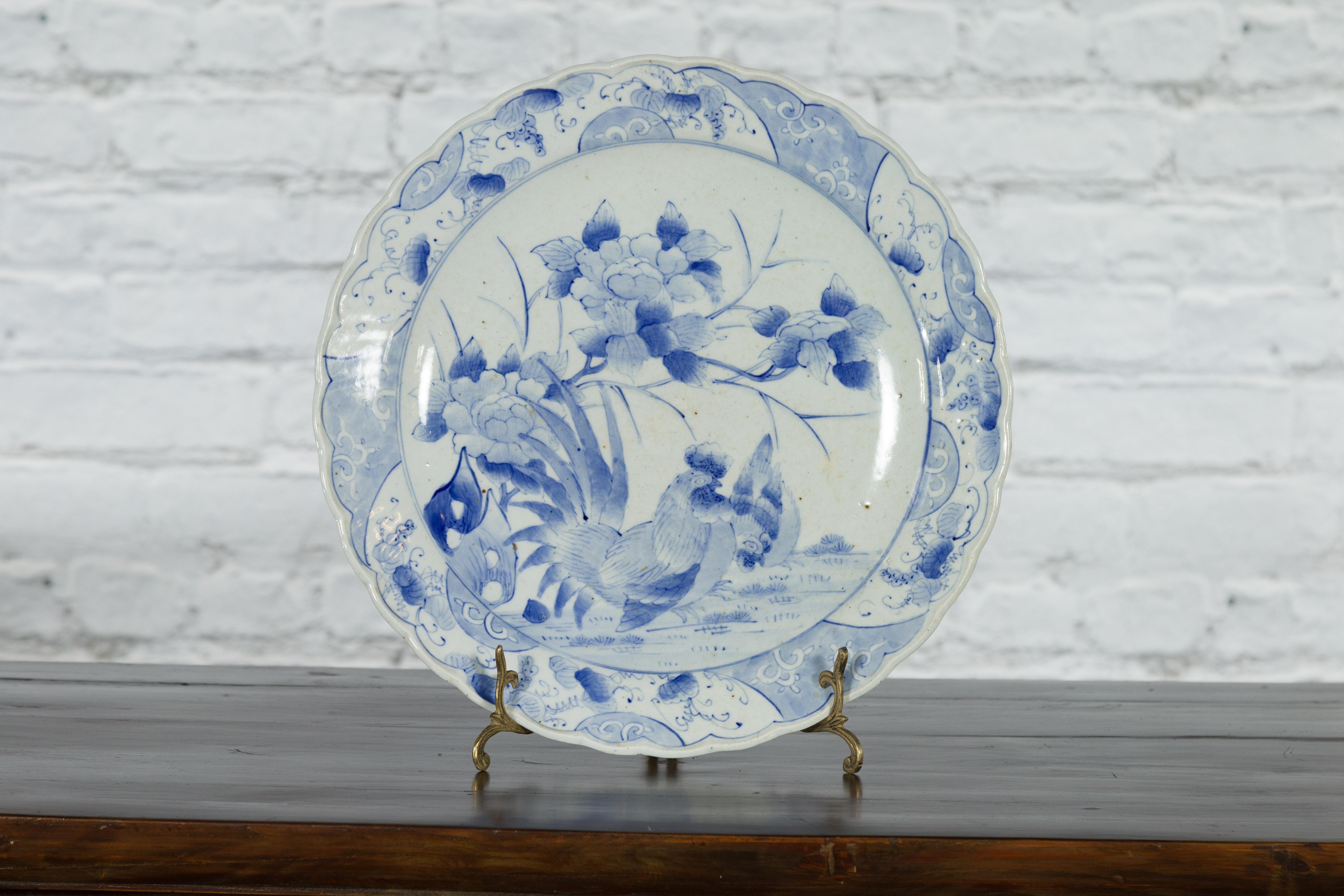 A Japanese porcelain plate from the 19th century, with hand-painted blue and white floral décor with a rooster and a hen. Created in Japan during the 19th century, this porcelain plate features a delicate blue and white décor depicting a peaceful