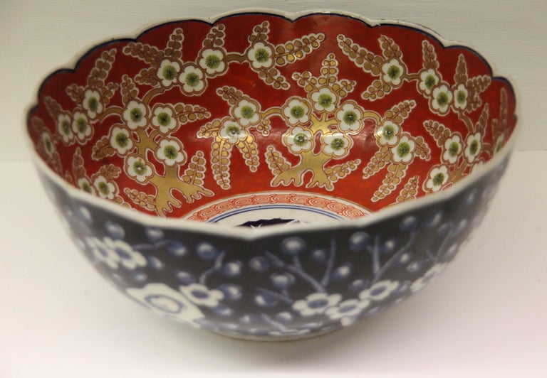 19th century Japanese Imari bowl, scalloped edge, with central medallion surrounded by gilded leaf and floral work on a deep orange background, the exterior with cobalt floral work and stylized design.