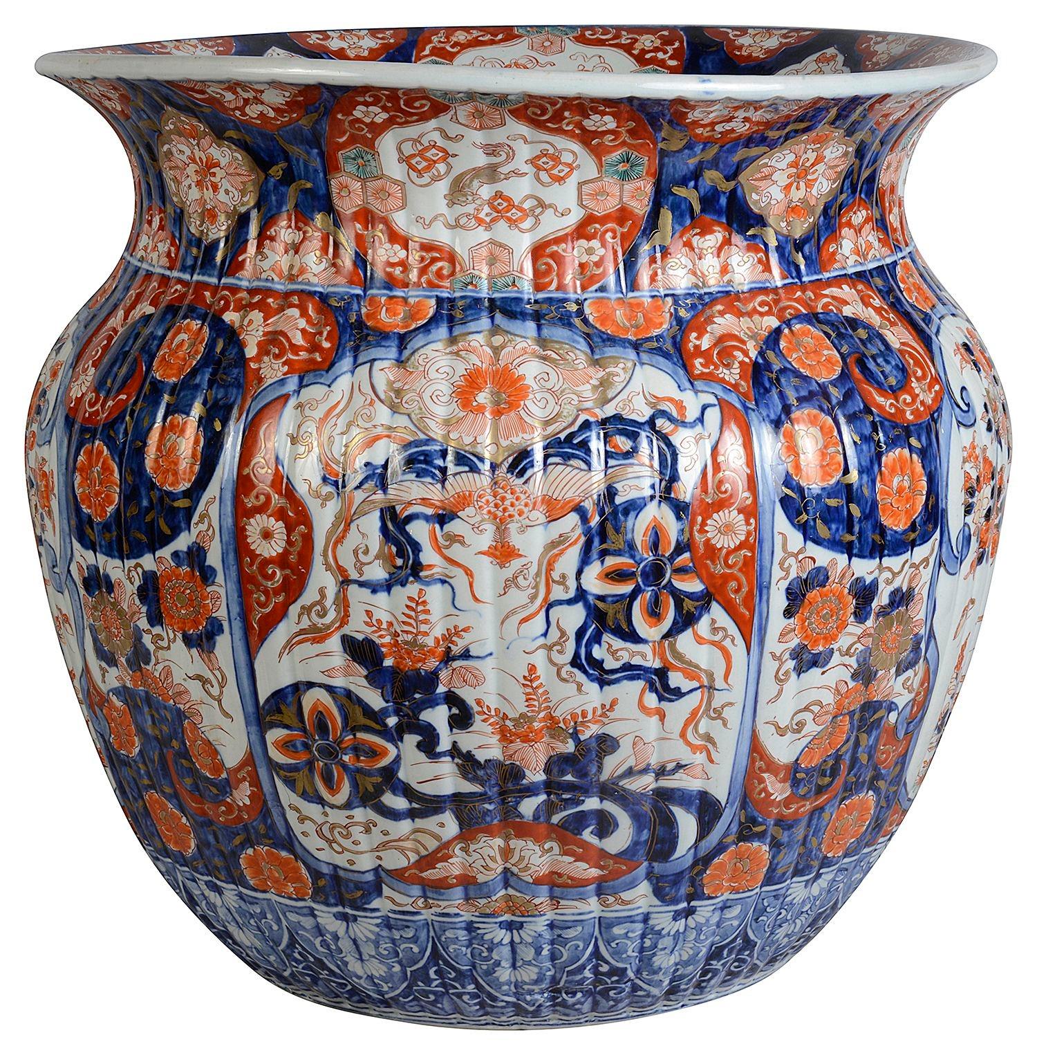 An impressive late 19th Century Japanese Imari porcelain jardiniere in the classic orange and blue Imari colours, with motif patterns to the boarders, inset hand painted panels depicting floral scenes to the ribbed body and gathered neck.

Batch 78