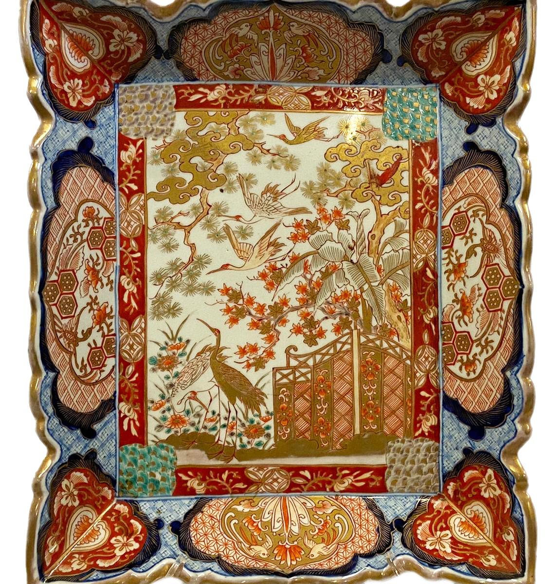 A very good quality late 19th century rectangular Japanese Imari plate, having classical red and blue colouring, classical scrolling motif decoration to the boarders, the painted inset central panel depicting exotic flowers and trees and a screen,