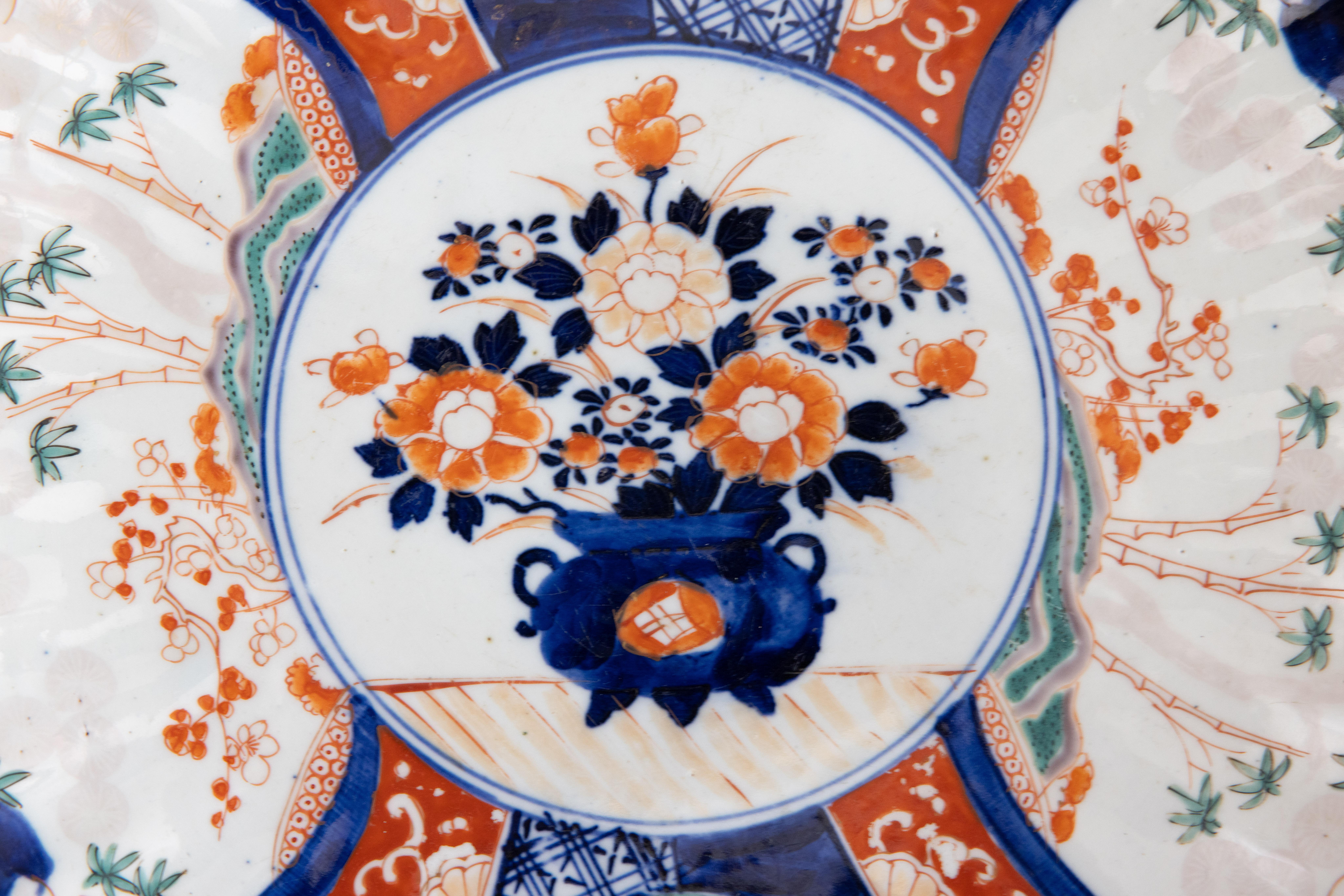A gorgeous 19th-Century Japanese Imari porcelain charger with a hand painted floral design in the traditional Imari colors. This fine large plate has lovely scalloped edges and is quite heavy, weighing over 2 1/2 lbs. It displays beautifully,