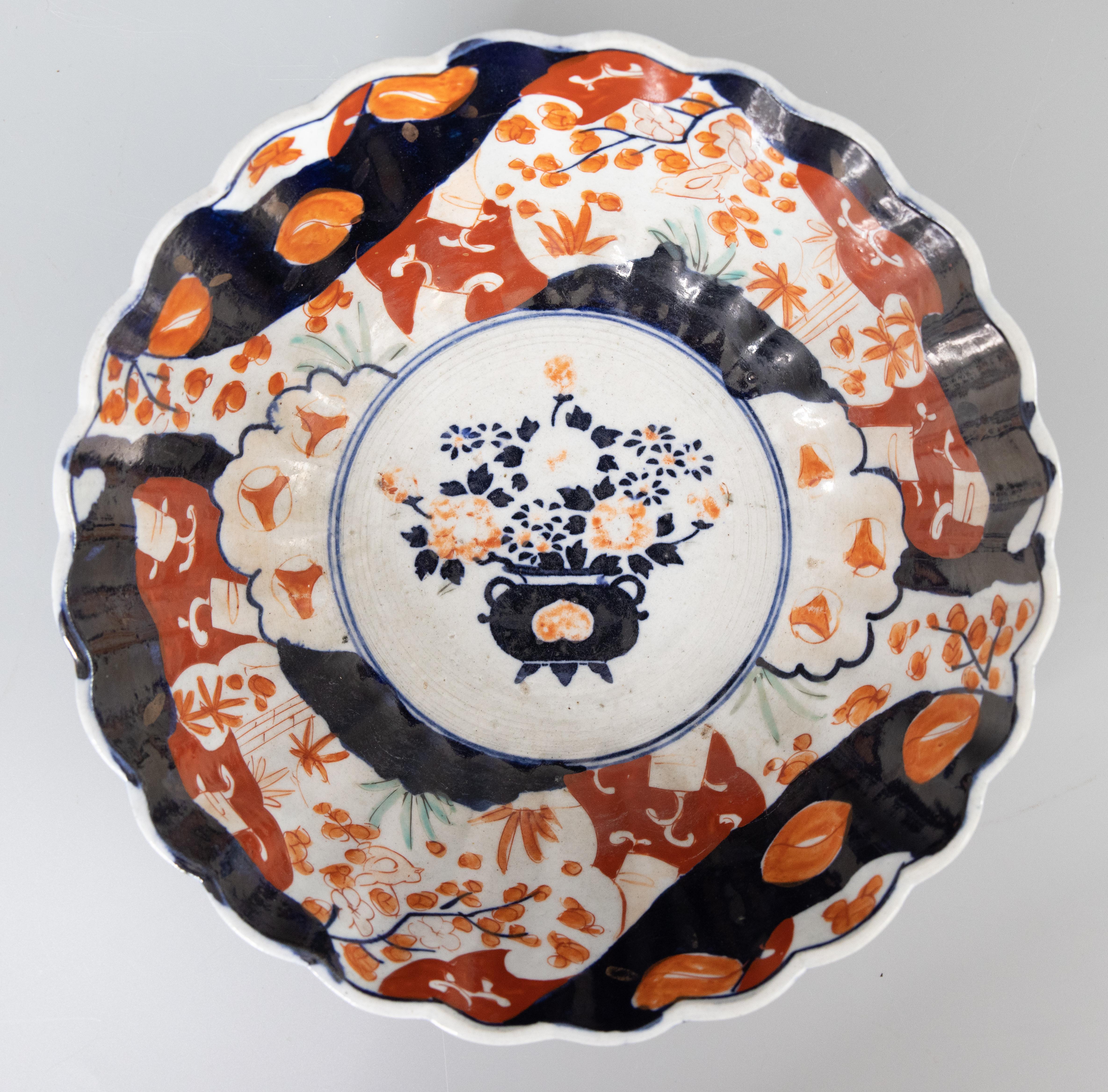 A gorgeous 19th-century Japanese Imari porcelain bowl with a hand painted floral design in the traditional Imari colors. This fine bowl has lovely scalloped edges, a fluted design, and displays beautifully. Decorative balls not
