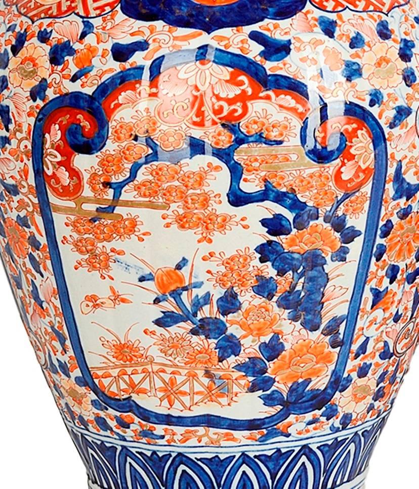 A good quality 19th Century Japanese lidded Imari vase, with dog of faux finial, the classical blue and orange ground having motif, flower and leaf decoration with inset panels of gardens with exotic birds and butterflies.