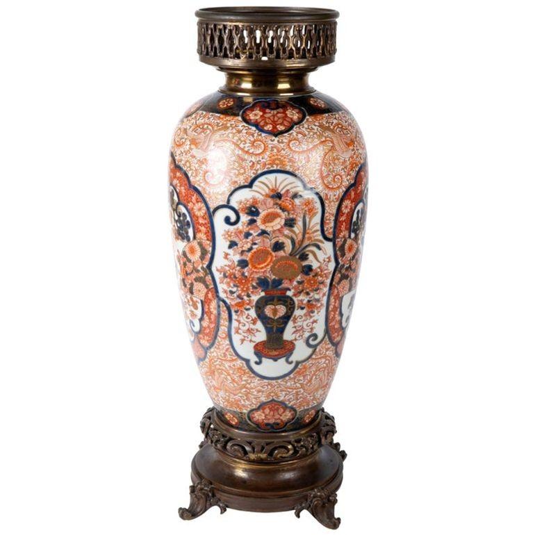 A very good quality 19th century Japanese Imari vase or lamp. Having classical Imari colors of oranges and blues, depicting flowers, motifs, and inset panels of children playing and vases of flowers. Mounted on bronze scrolling base and having a