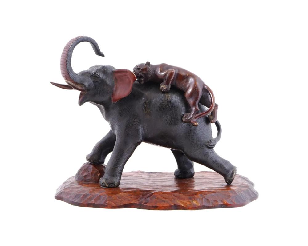 An antique Japanese, Meiji period, patinated bronze okimono sculpture. The sculpture depicts a scene with an elephant and a tiger. Mounted on a hand carved wooden base. Circa: late 19th century. Antique and Vintage Asian and Oriental Bronze