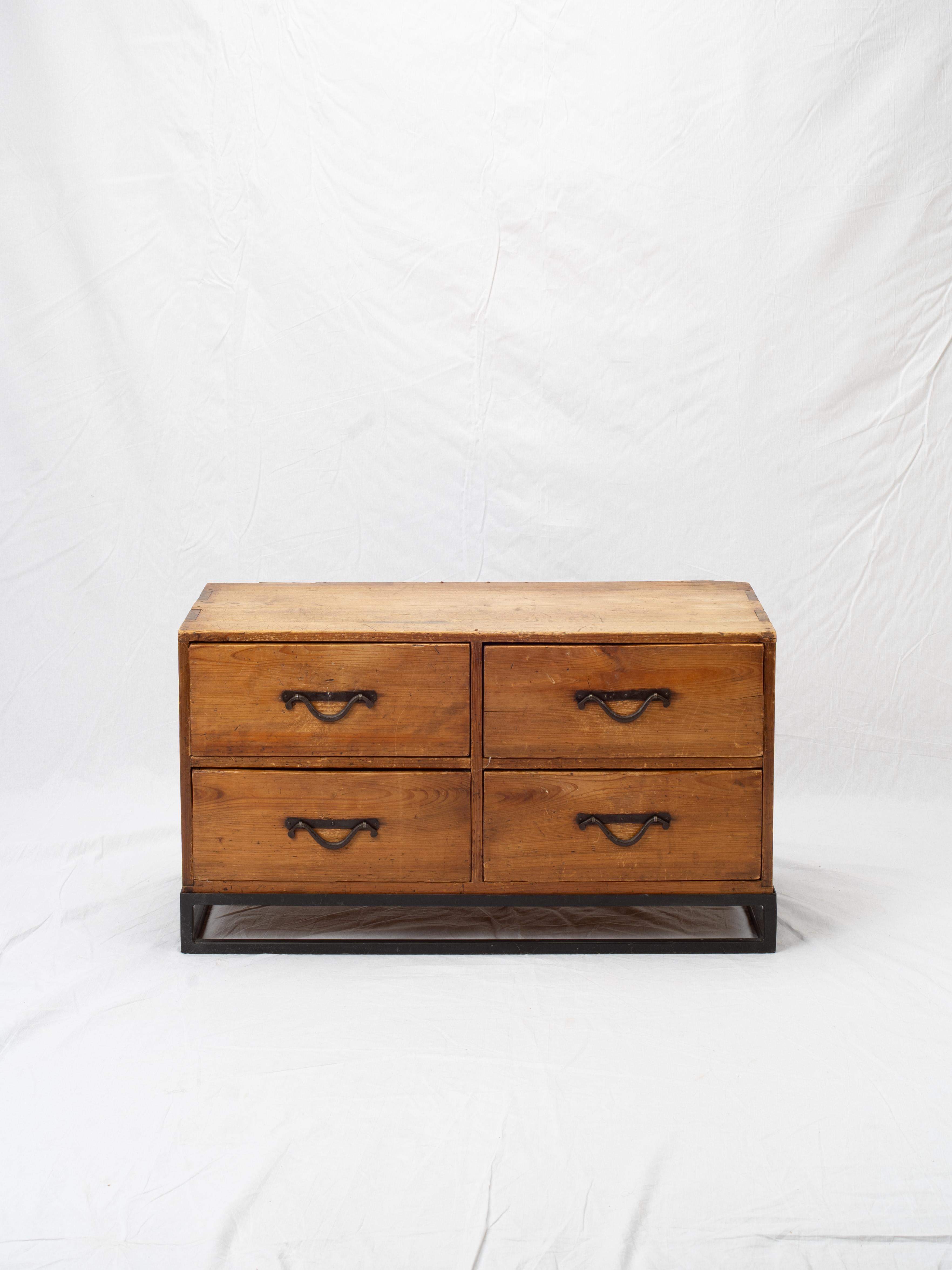 Realizzata in legno di Sugi (cedro giapponese), questa cassapanca per abiti ha un design minimalista e poggia su un telaio in ferro. Il tavolino è impreziosito da una ferramenta in ferro annerito, con 4 cassetti e maniglie elegantemente