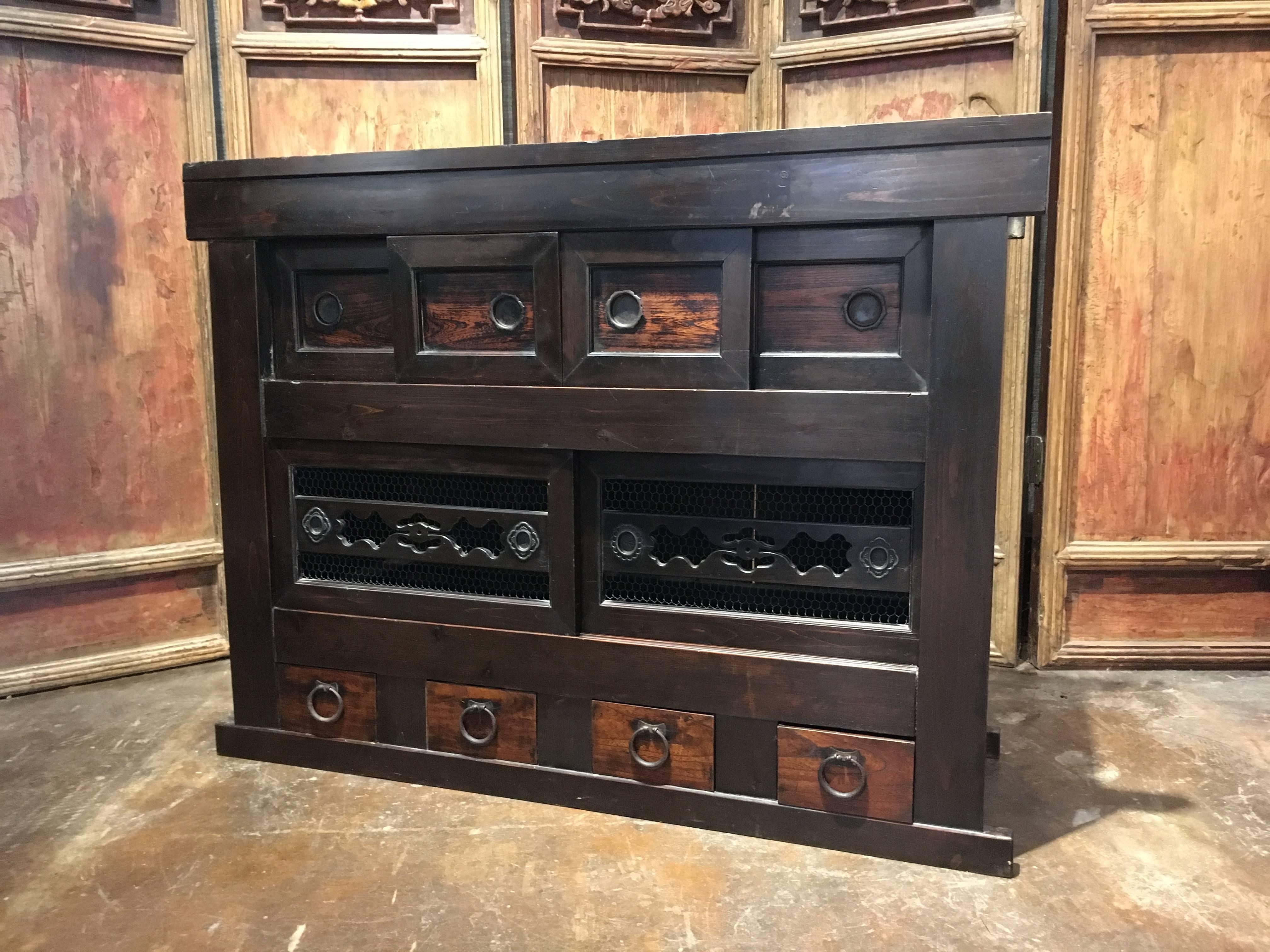 An attractive late 19th century Japanese Meiji period kitchen storage cabinet, called a mizuya.
The cabinet crafted of sugi (Japanese cypress), with keyaki (elm) drawers and door faces, and hand-forged iron fittings.
The cabinet featuring two