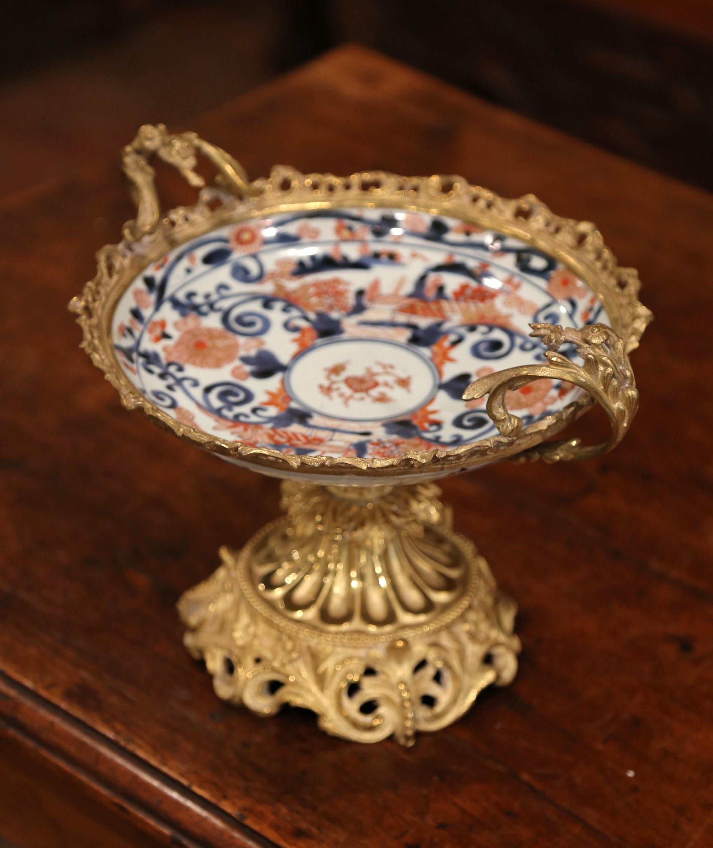 Decorate a console with this antique Imari bowl for a small dose of oriental design in your home. Crafted in Japan circa 1860, the circular porcelain vide-poche sits on an ornate Louis XV gilt bronze stand. The bronze setting reflects an ornate,