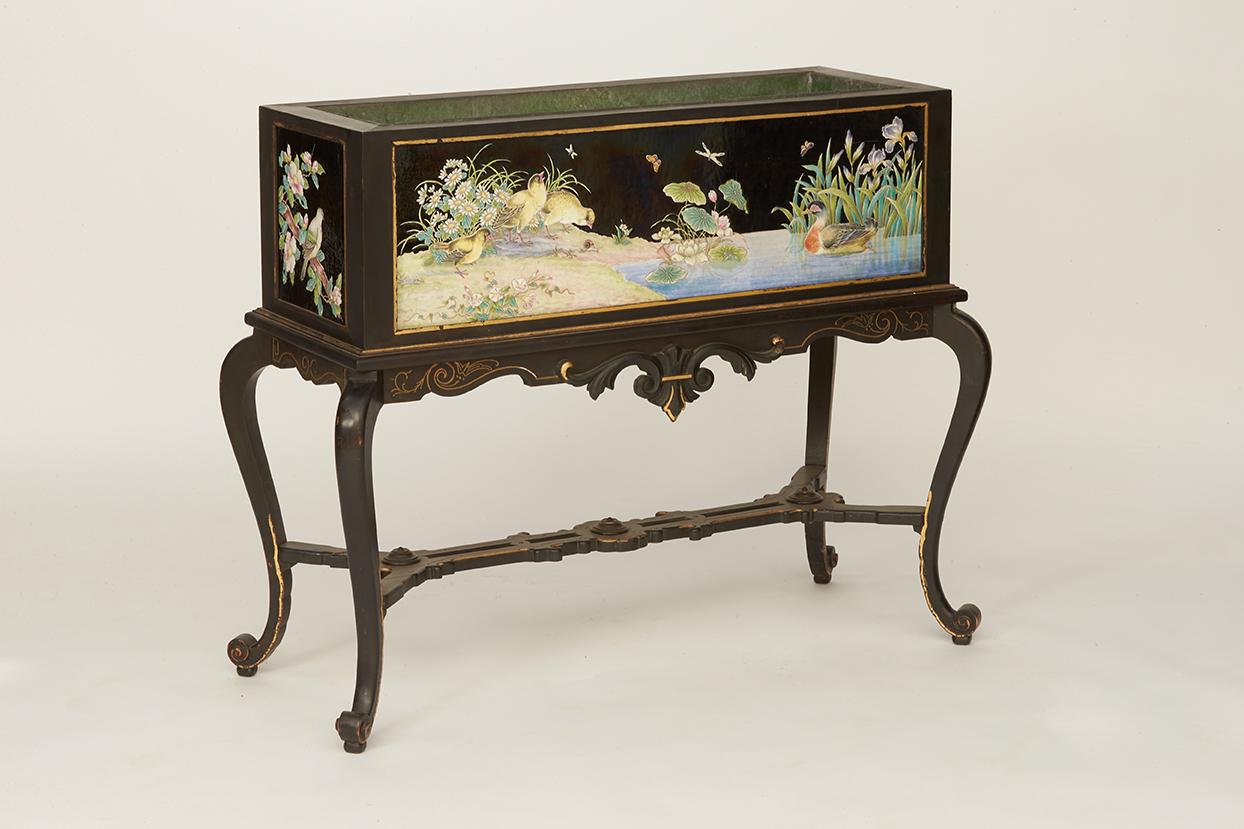 This planter imagined by Eugène Collinot has a volute base. The spacer is stylized and very richly worked X-shaped. The rectangular container has a large branch of a Japanese cherry tree with pink flowers and green leaves on one side. Three