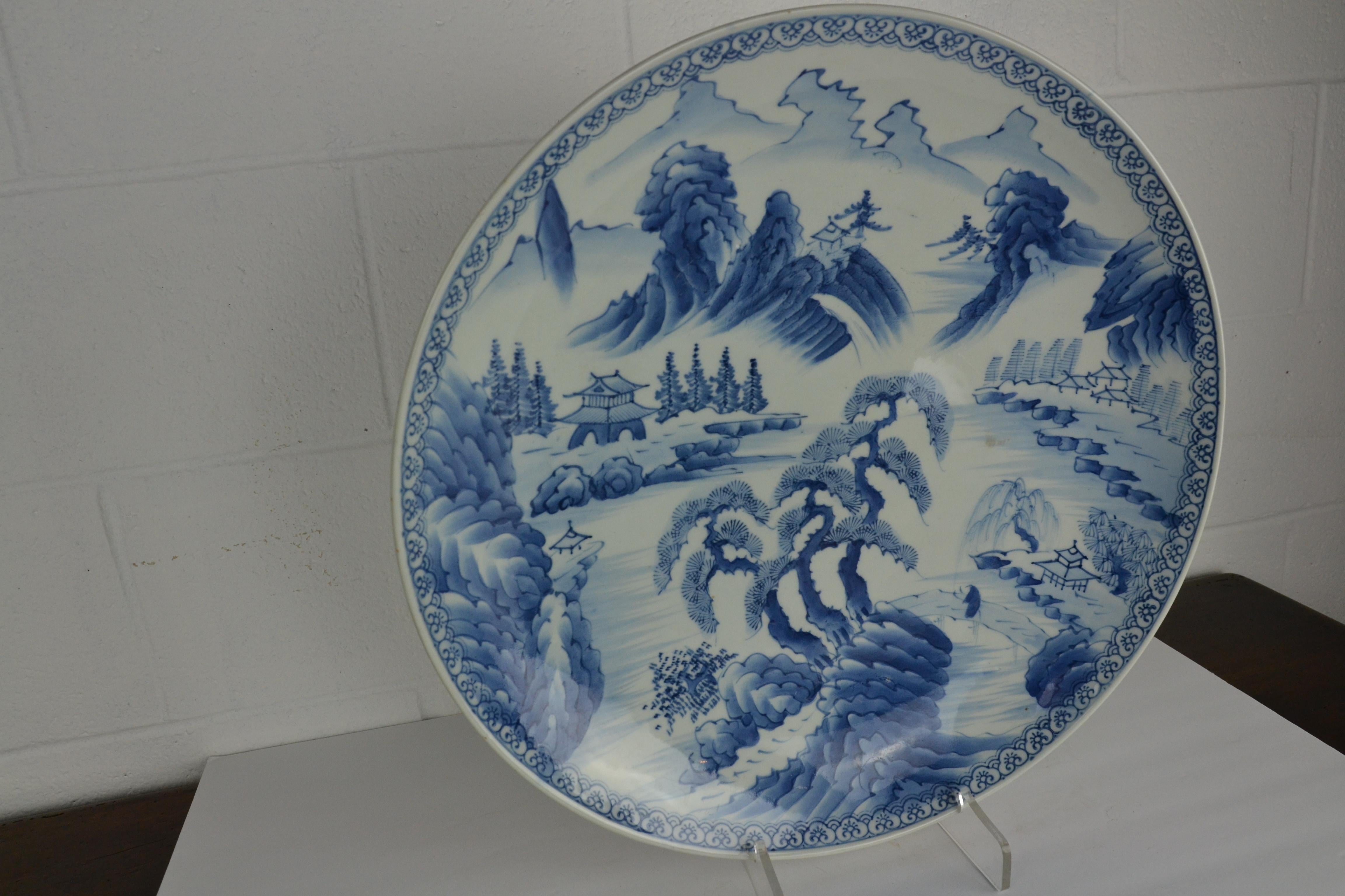 A large blue and white Japanese platter from the late 19th century. Decorated with a landscape scene with trees, hills and homes. Nice blue tint the white ground.