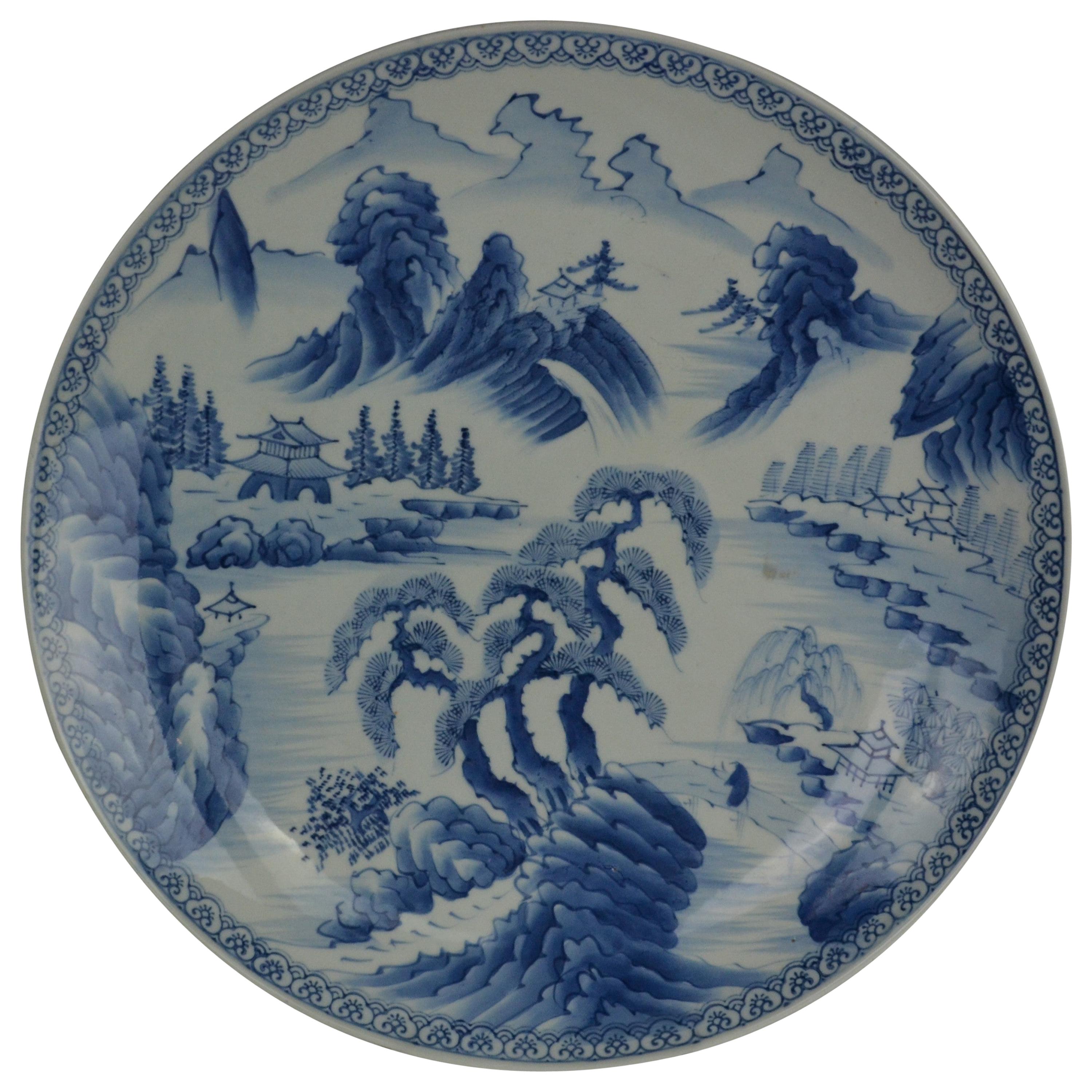 A large blue and white Japanese platter from the late 19th century. Decorated with a landscape scene with trees, hills and homes. Nice blue tint the white ground.