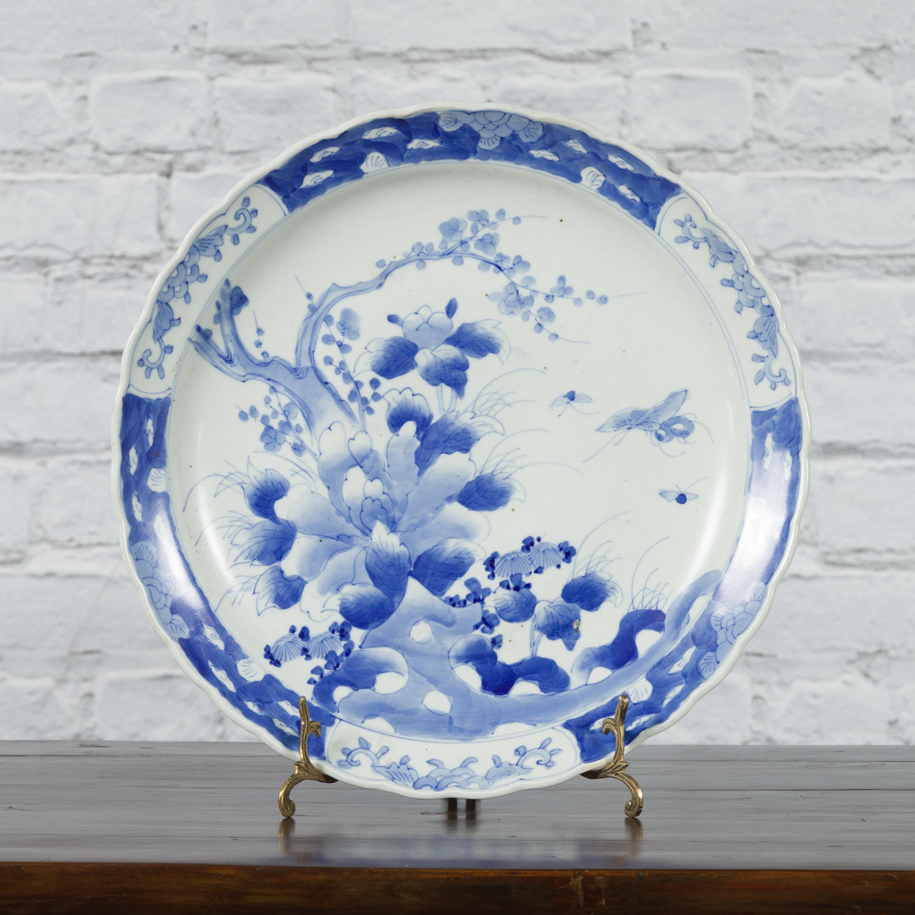 A Japanese Imari porcelain plate from the 19th century, with hand-painted blue and white tree, foliage and butterfly décor. Created in Japan during the 19th century, this Imari porcelain plate features a delicate blue and white décor depicting an