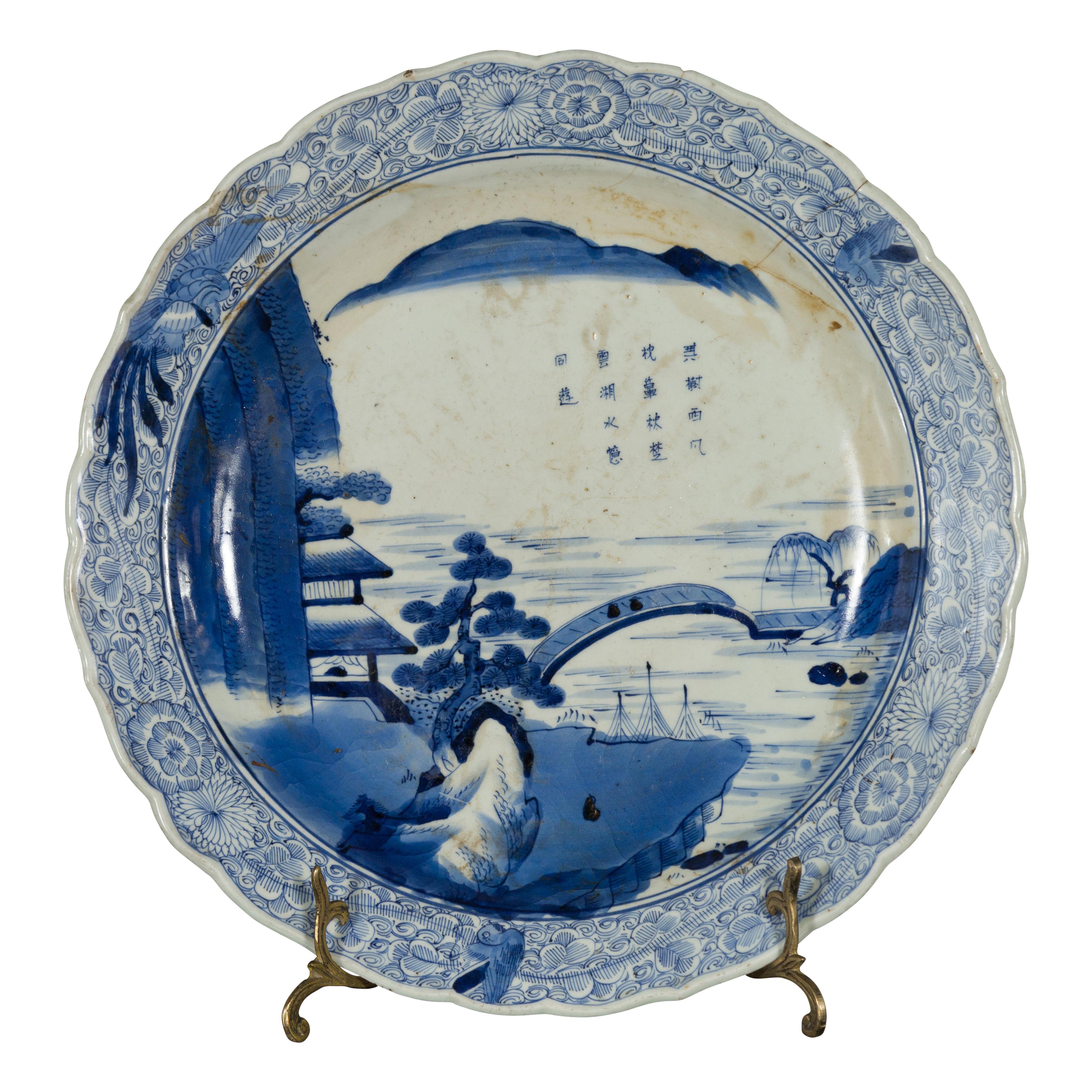 Ein japanischer Imari-Porzellanteller aus dem 19. Jahrhundert mit handgemaltem blau-weißem Berg-, Baum-, Architektur- und Brückendekor. Dieser Teller aus Imari-Porzellan, der im 19. Jahrhundert in Japan hergestellt wurde, zeigt ein zartes