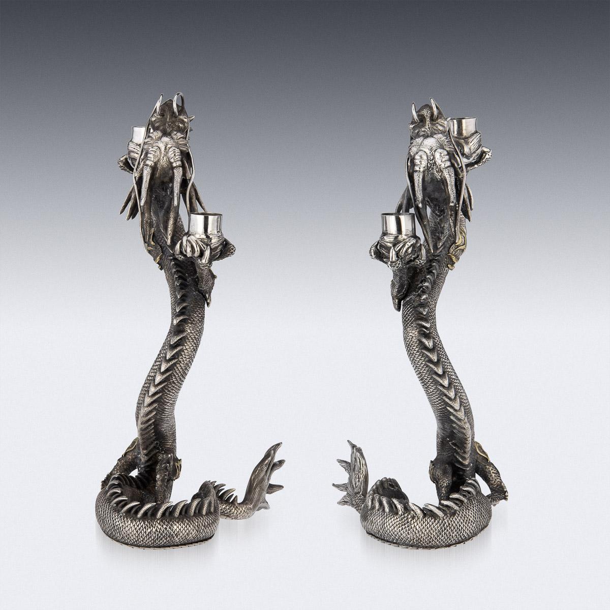 19th Century Japanese Meiji period silver dragon shaped candelabras. Cast and carved as a serpentine water dragons, spiked body, with mouth open, with both arms up holding the candlesticks. The piece dates to the Meiji period (1890-1912), Marked