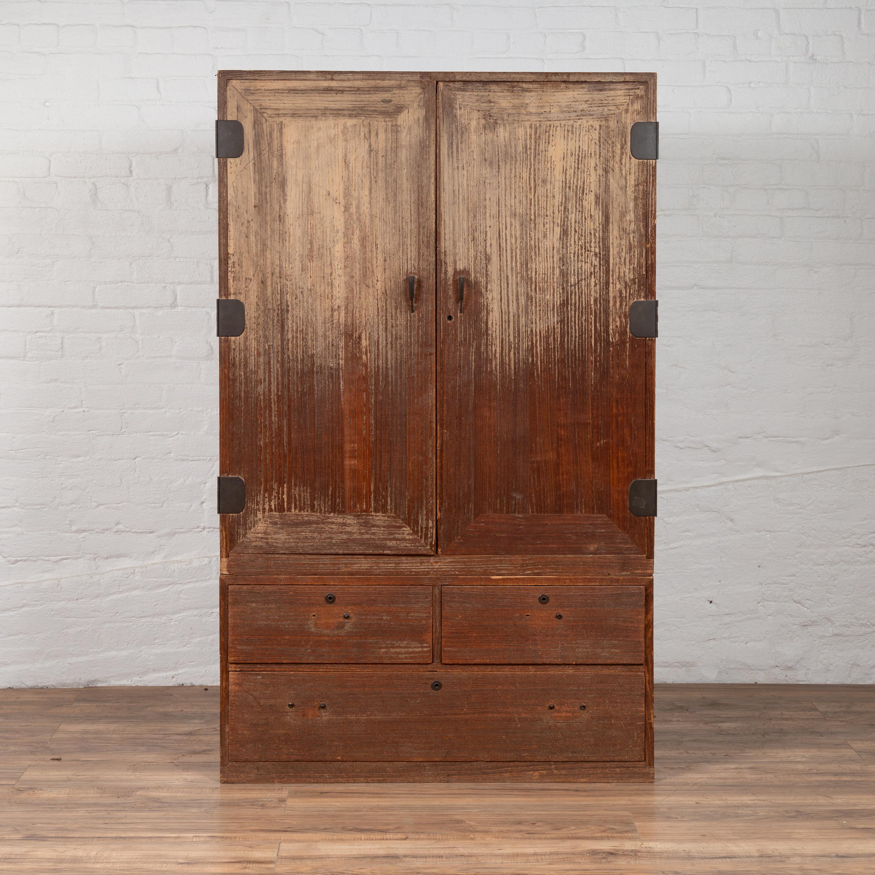 An antique Japanese two-section kiri wood wardrobe from the 19th century, with ombre finish. Born in Japan during the 19th century, this exquisite kiri wood armoire is made of two separate sections which, placed above one another, create a beautiful