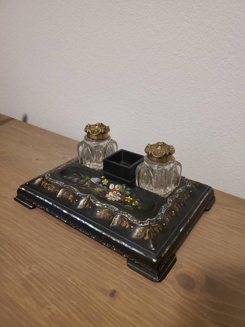 An English Victorian Japanned papier mache desk set with mother of pearl inlay and elaborate rich polychrome painted flower decoration. 

The charming antique features an ebonized double inkwell, retaining the original fitted pair of square faux