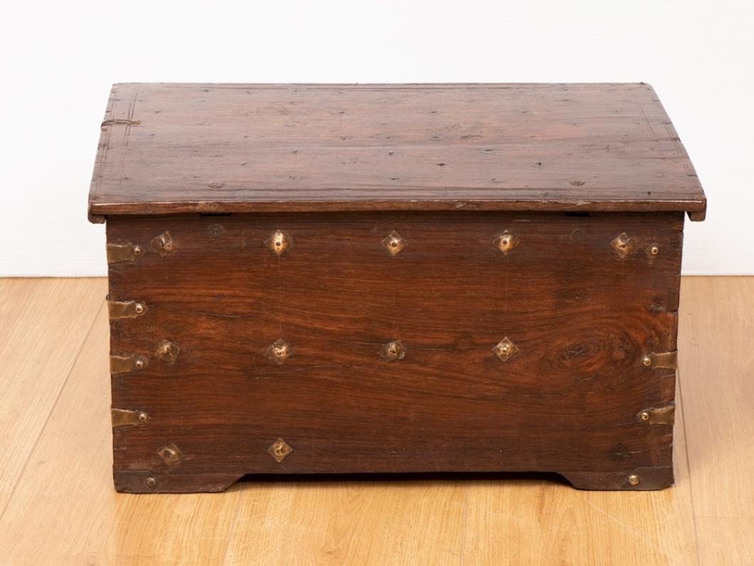 An antique Indian jewellery box with three small drawers at the front, lidded top and handles. It is decorated with brass work and bindings.