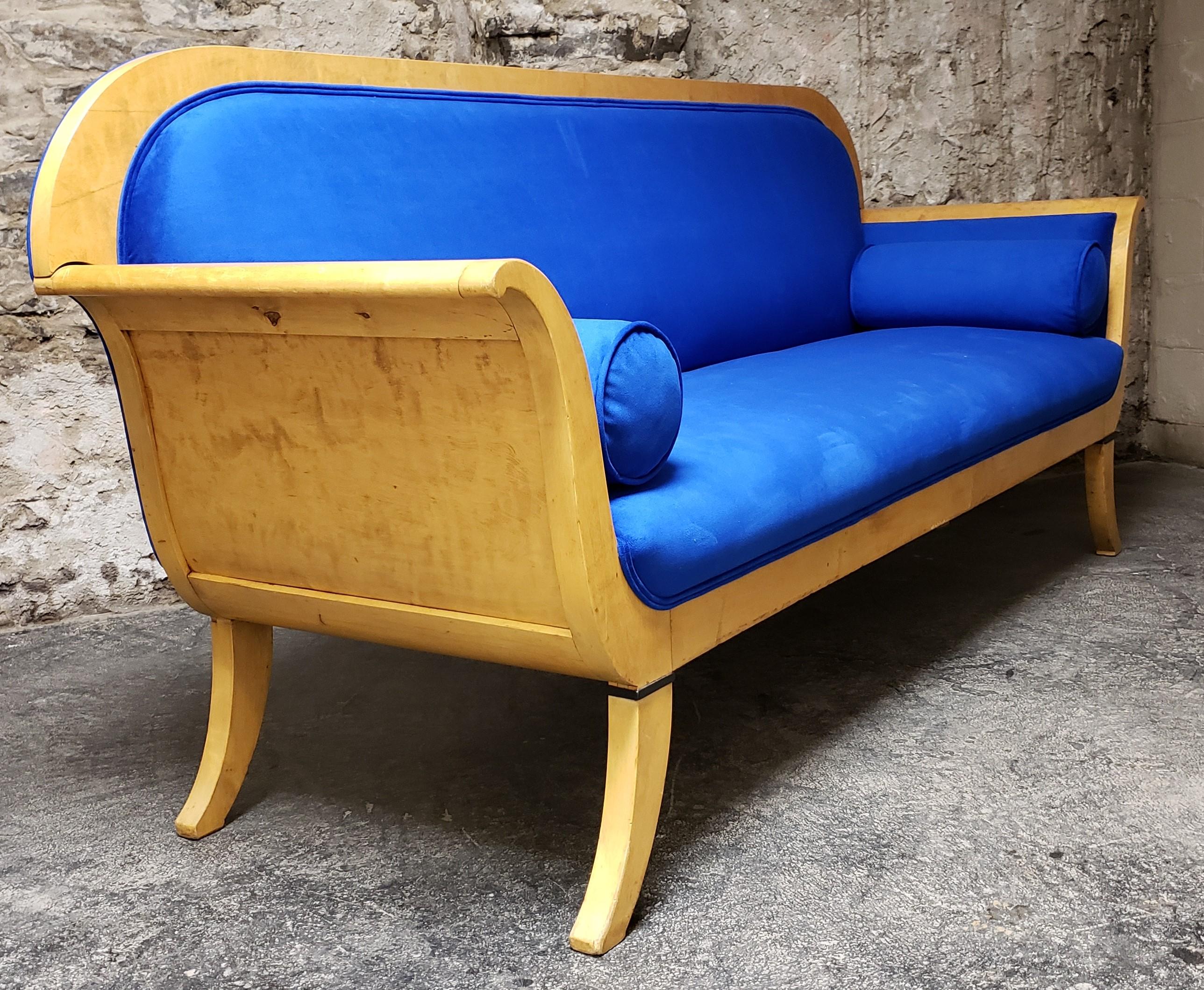 A Karl Johann style Swedish Biedermeier satinwood sofa, circa 1830. This antique yet Minimalist designed sofa is freshly upholstered in a handsome royal blue velvet with two custom rolled pillows. Because the sofa is deep it is extremely comfortable