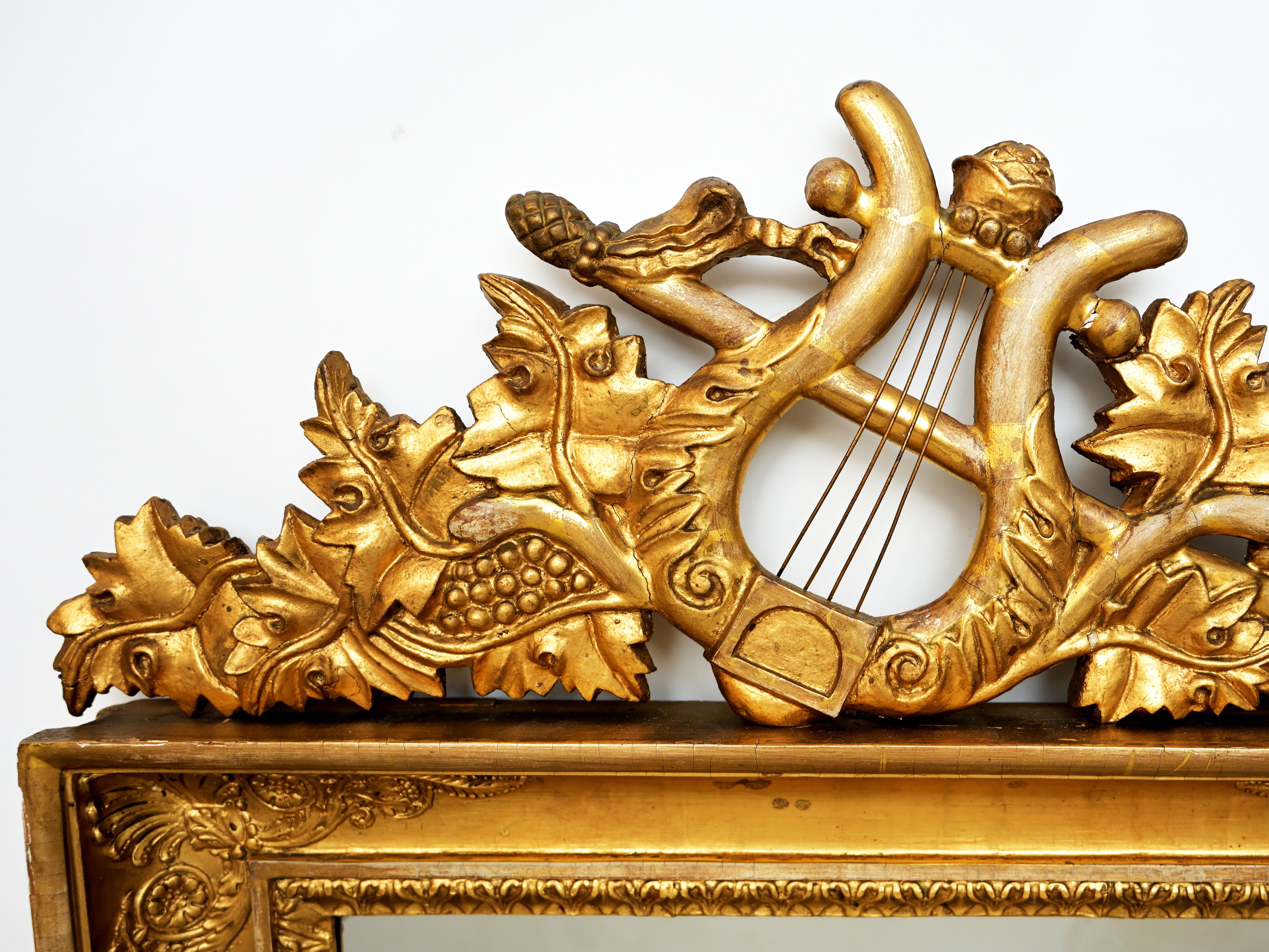 A Swedish Karl Johan period carved and giltwood girandole mirror with rectangular frame surmounted by trophy medallion with lyre and wreath motif and 2 brass candle arms c. 1830