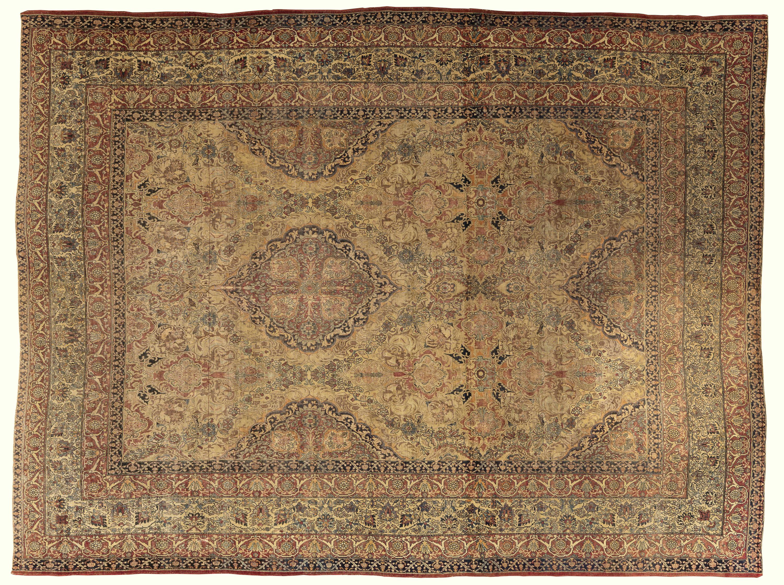 Ce tapis de Kerman du XIXe siècle présente un jeu raffiné de tons neutres de beige, de terre cuite, de bleu tendre et de charbon de bois, disposés dans un médaillon richement étagé. Sa surface révèle un réseau dense de vignes enroulées, de palmettes
