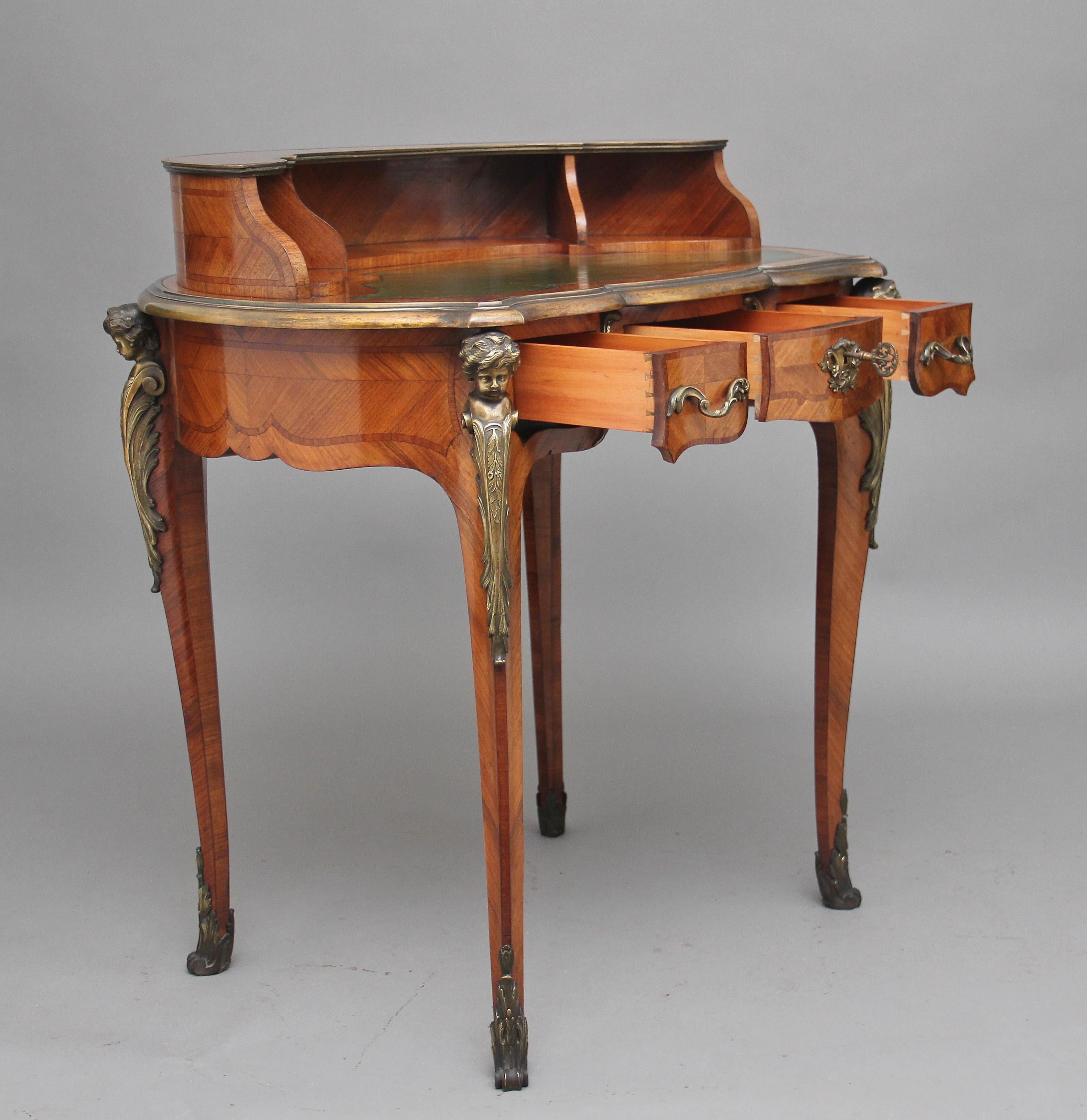 A free standing 19th century French Kingwood and ormolu writing table, having a curved superstructure with divided compartments, the shaped top with a brass moulded edge, green leather writing surface decorated with blind and gold tooling, the table