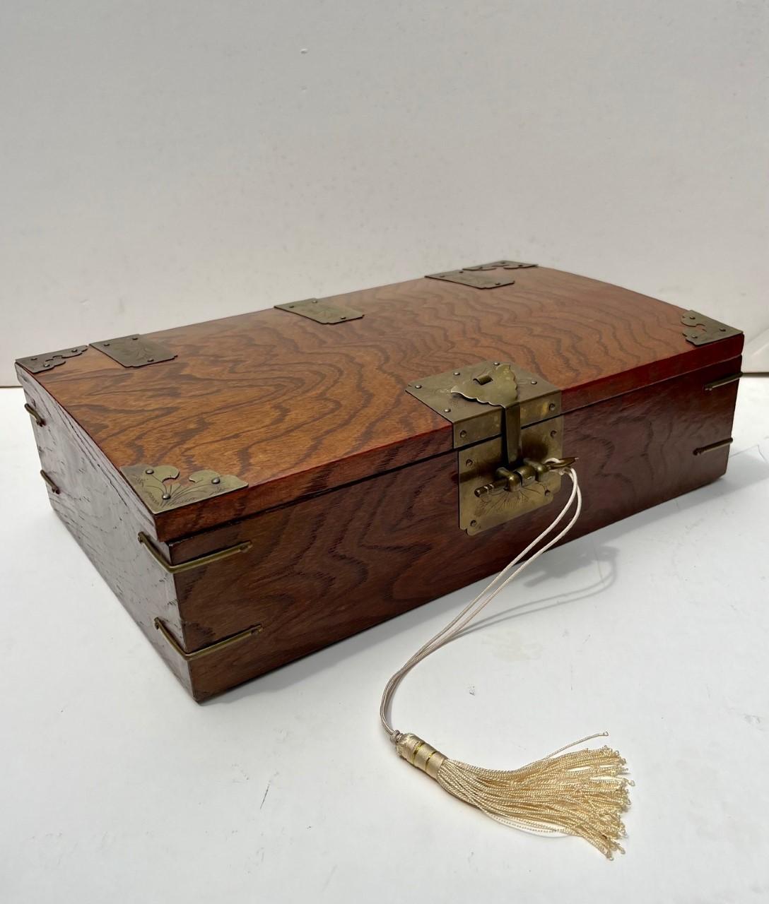 An antique Korean wooden document box from the late 19th century. These hand-crafted valuables box, with Manchurian influence, has a strong and beautiful patterned wood grain and extensive decorative and structural cut brass hardware elements. The