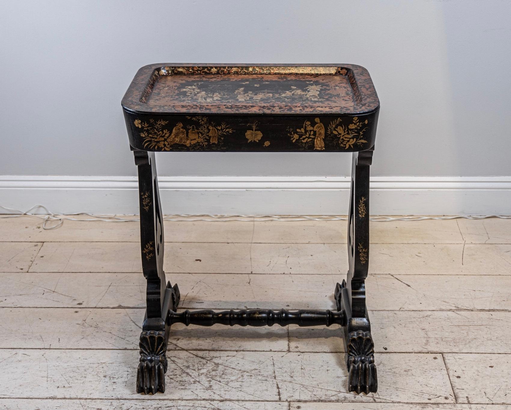 Late 19th century lacquered chinoiserie decorated side/tray table. Most likely to be French and converted from a sewing table at some point over the years.

The decoration which is over the body and lyre shaped sides is of female figures, flowers,