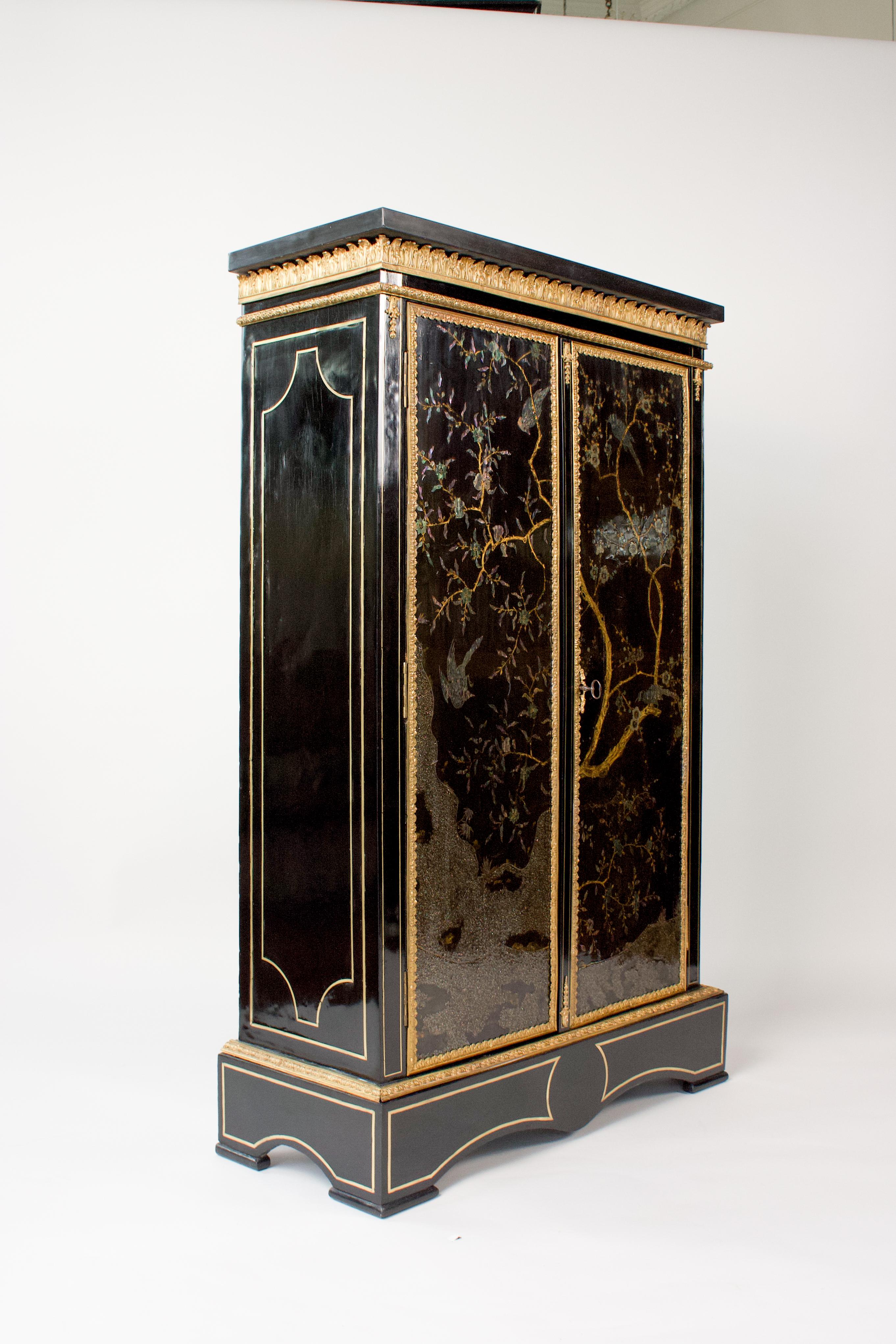 Petite 19th-century armoire in ebony veneer, adorned with brass inlay decoration.  It opens with two doors with panels of Chinese lacquer from the 17th century, featuring birds on flowering branches inlaid with mother-of-pearl.
Beautiful gilded