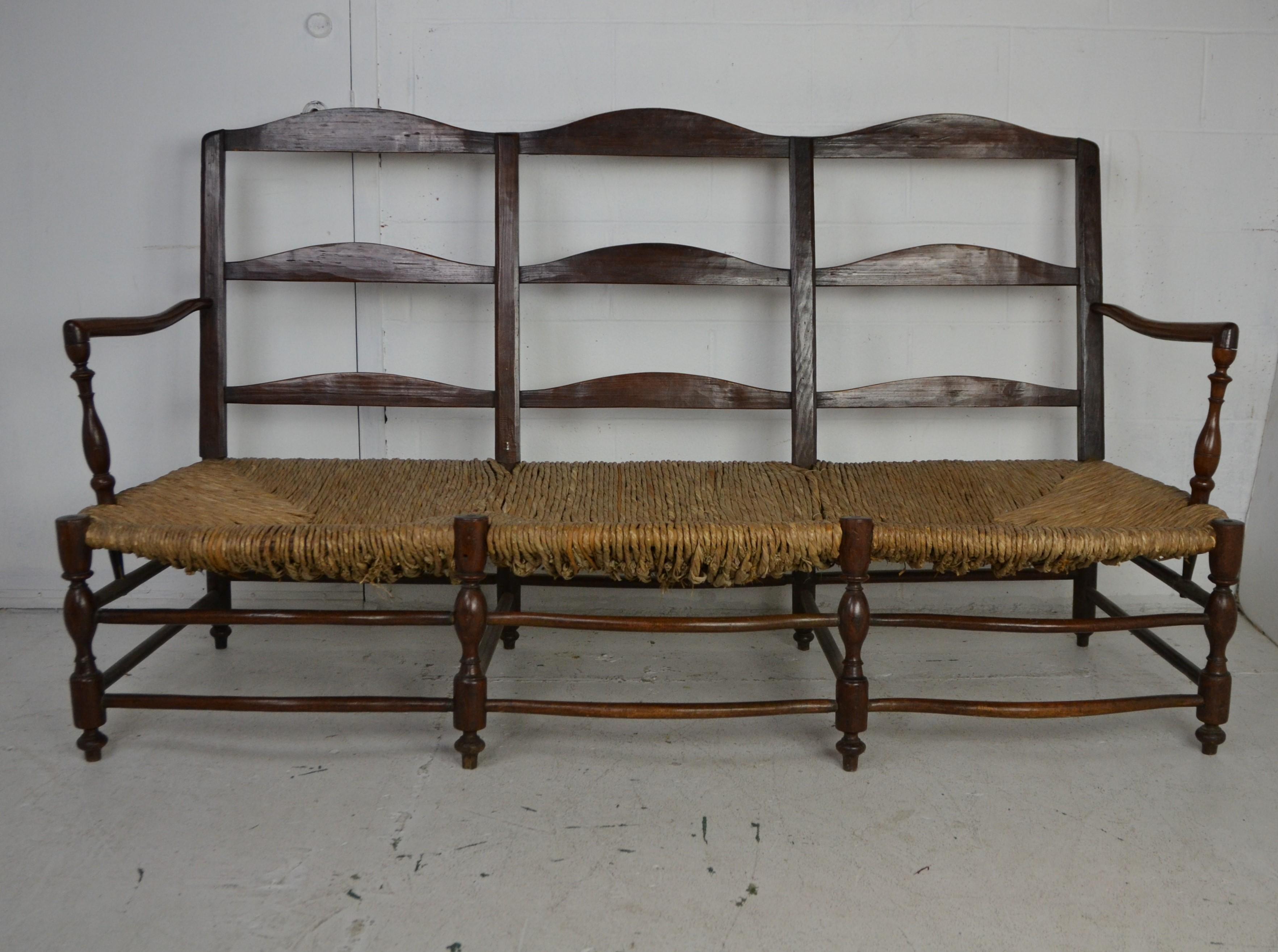 19th century French a 3 seat Ladderback Settee with rush seat and newly upholstered seat cushion. Walnut frame with turned legs and crinoline stretchers.