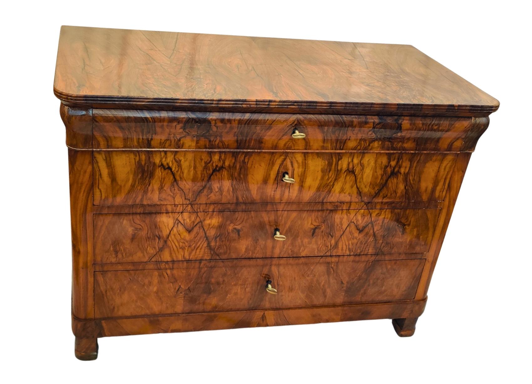 An early South German Biedermeier chest of drawers, circa 1825, featuring four drawers with stunning bookmatched walnut veneer on a softwood carcass. The beautifully grained walnut root veneer is present on all visible surfaces, including the top,