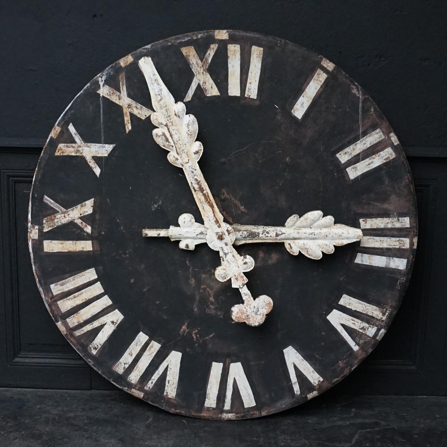 Decorative heavy large black metal church clock face with white roman numerals. 
Very elegantly designed white metal hands to set time to your hand. 
On the back; part of a, not functioning, motion work. 

It is in a lovely patinated as found