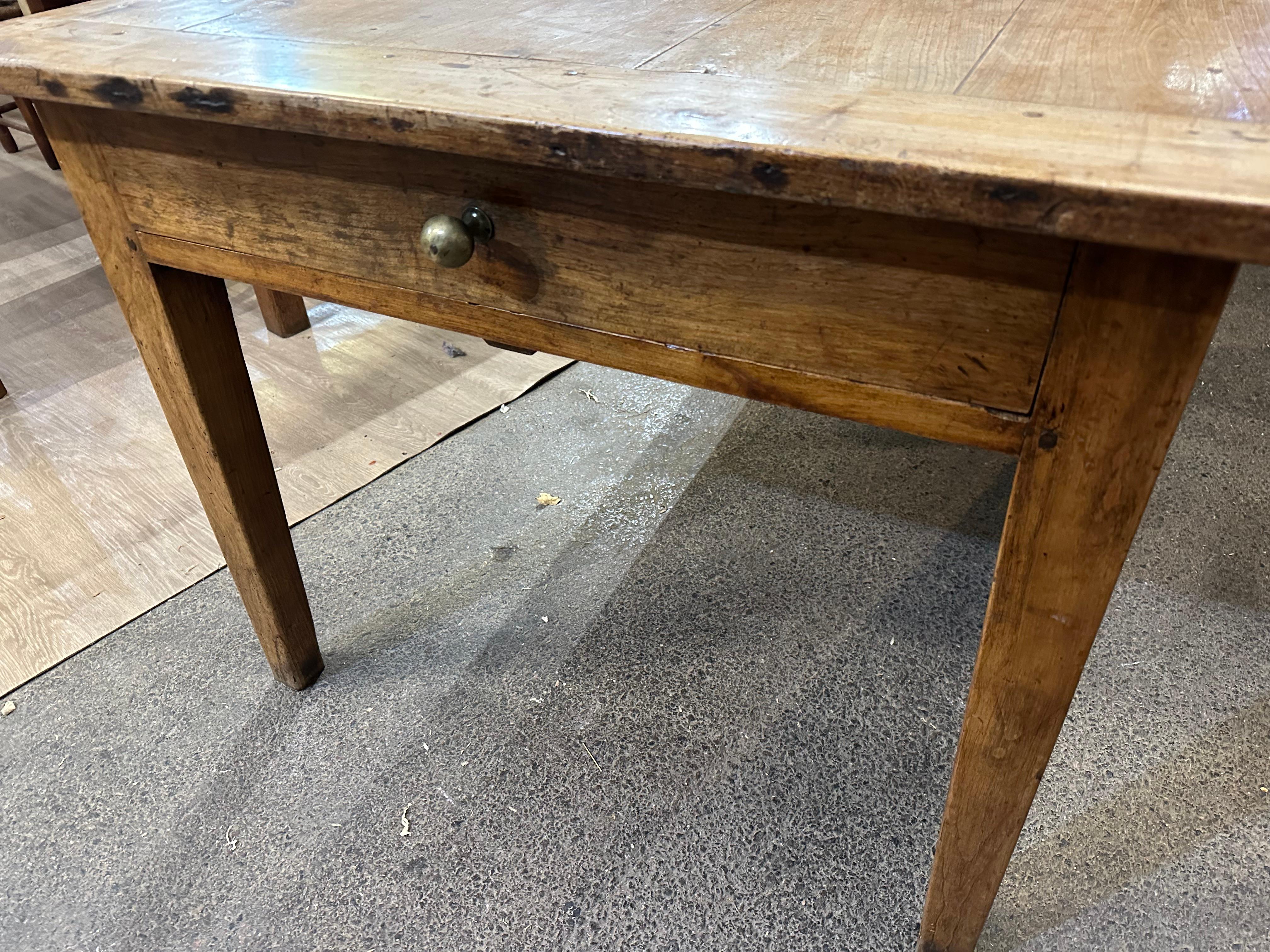 Table de ferme en cerisier du 19ème siècle avec une belle patine et une couleur claire. Elle présente un beau plateau large soutenu par de solides pieds fuselés et comprend un tiroir à l'une de ses extrémités. Cette superbe table de ferme est une