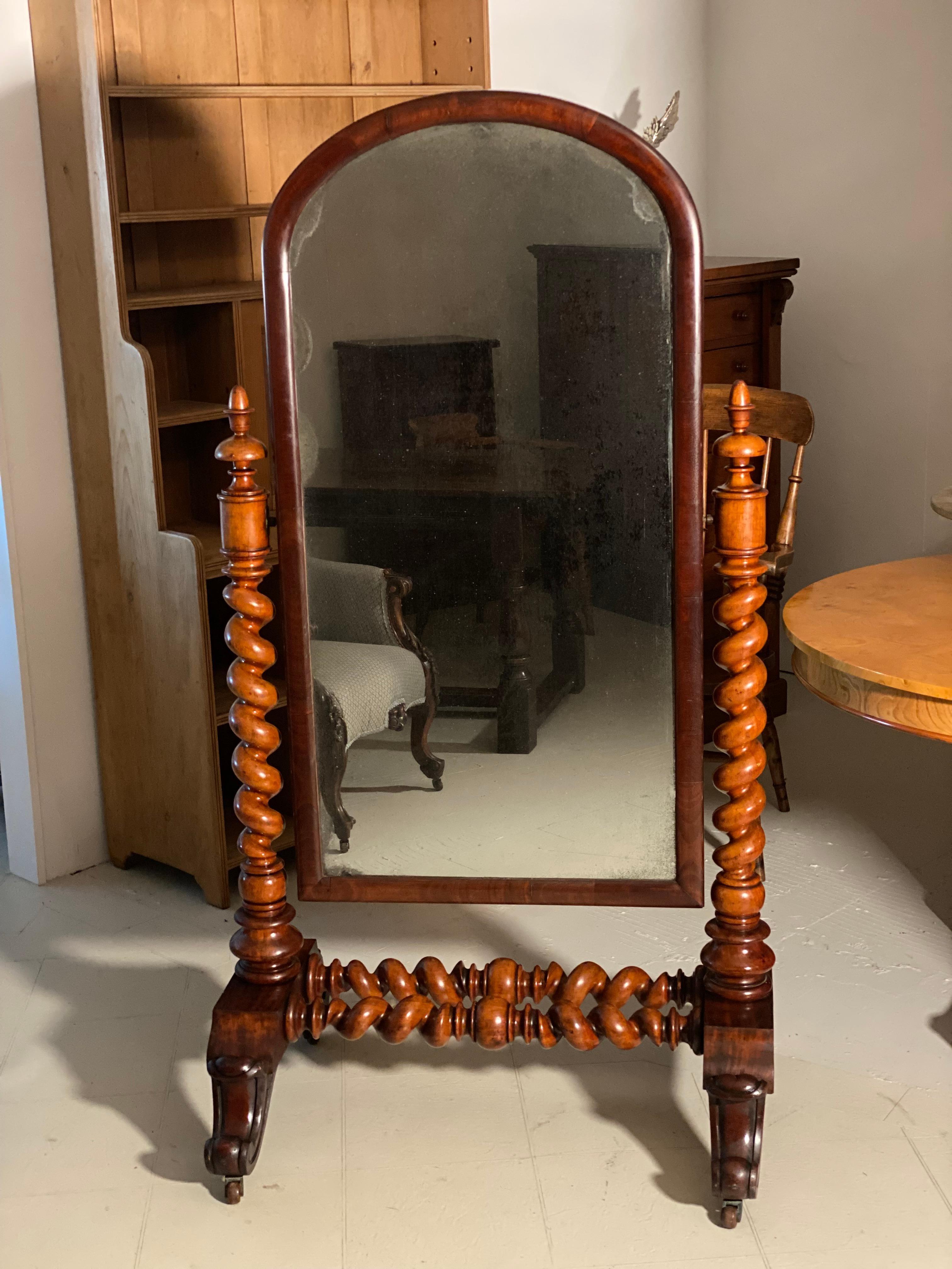 A large antique cheval mirror dating to the 1880’s. The mirror is made from mahogany with twisted columns sitting on a carved base with its original castor’s. The mirror is fully adjustable and can be set to any angle. It retains the original mirror