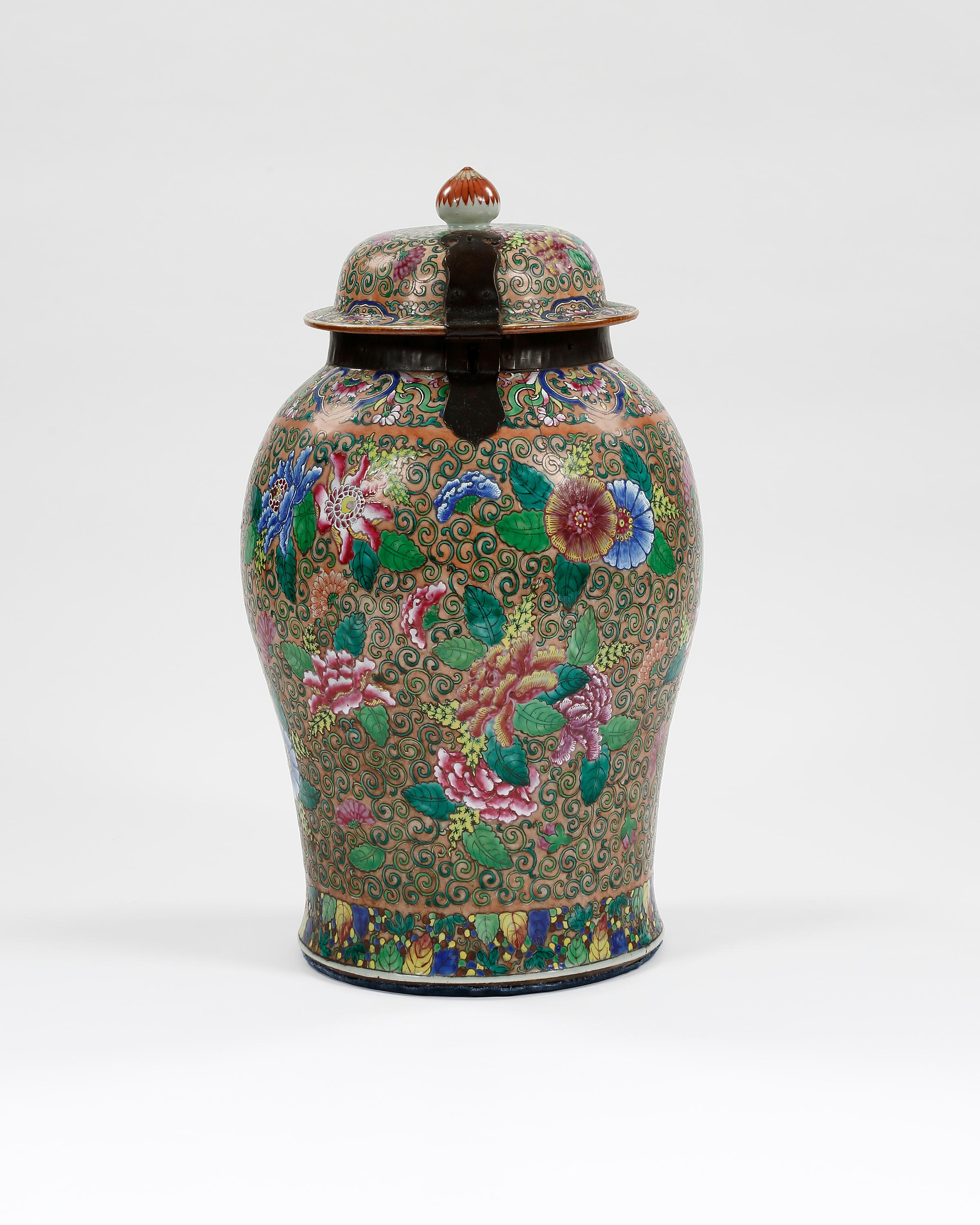 A 19th century large Chinese lidded storage jar with brass strap hinges, possibly for holding tea. Finely enamelled decoration of exotic flowers with vibrant colours of pinks, blues and greens.